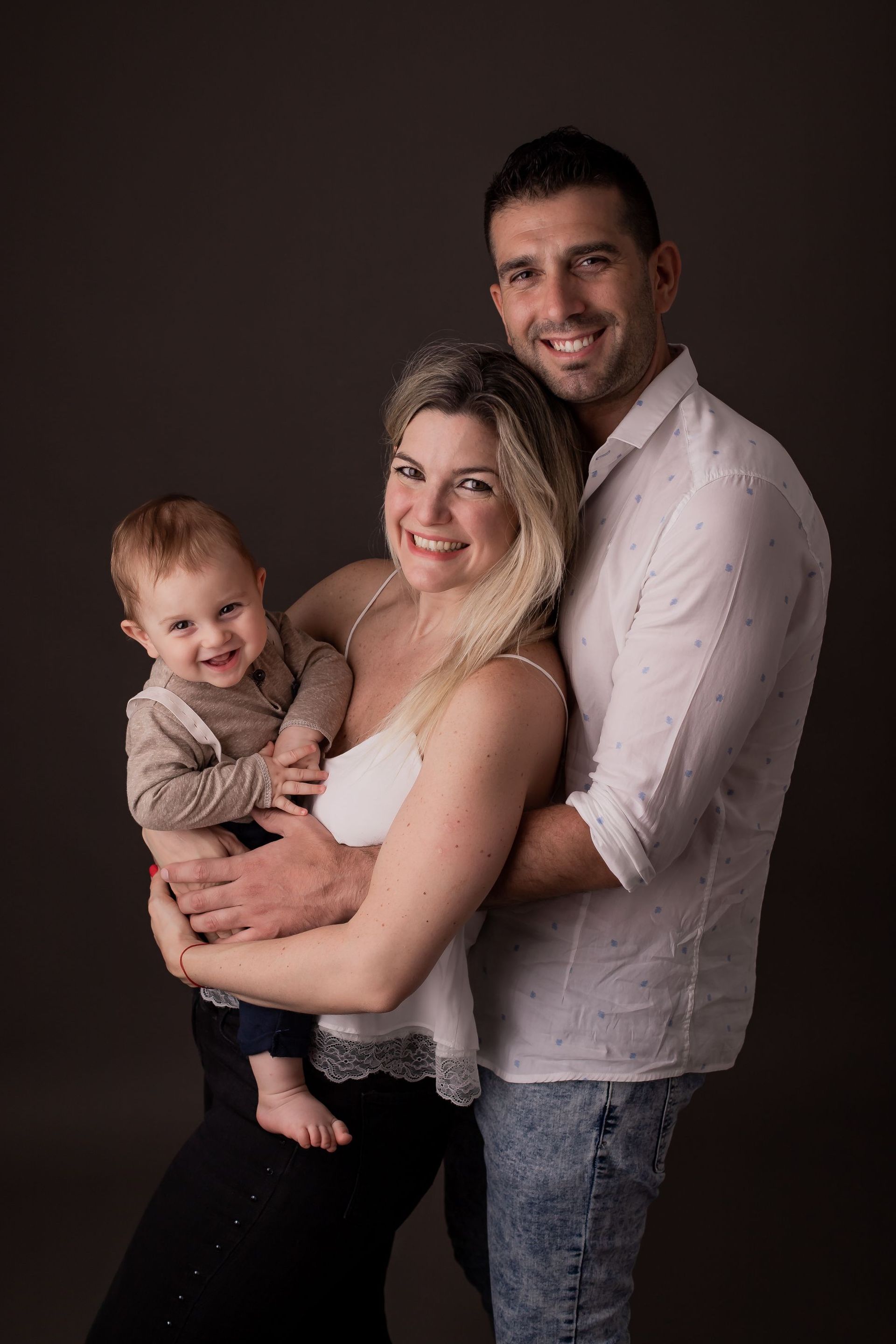 Un hombre y una mujer sostienen un bebé en sus brazos.