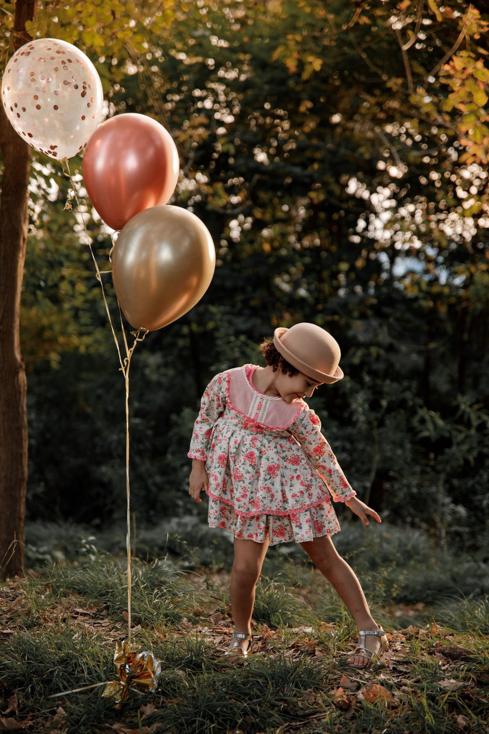 Una niña sostiene un montón de globos en un parque.