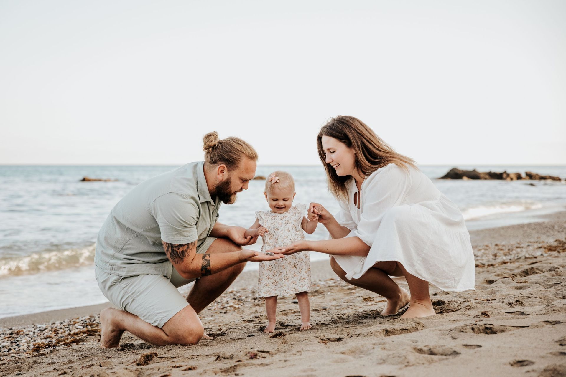 Una familia está jugando con un bebé en la playa.