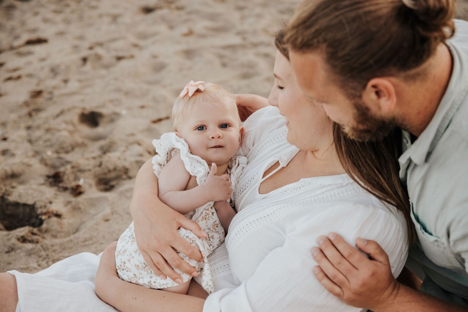 Un hombre y una mujer sostienen un bebé en la playa.