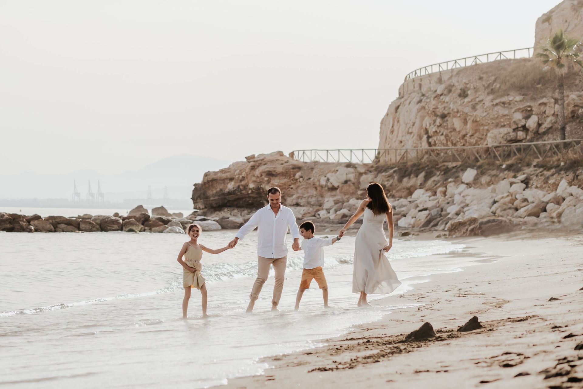 Una familia camina por la playa tomados de la mano.
