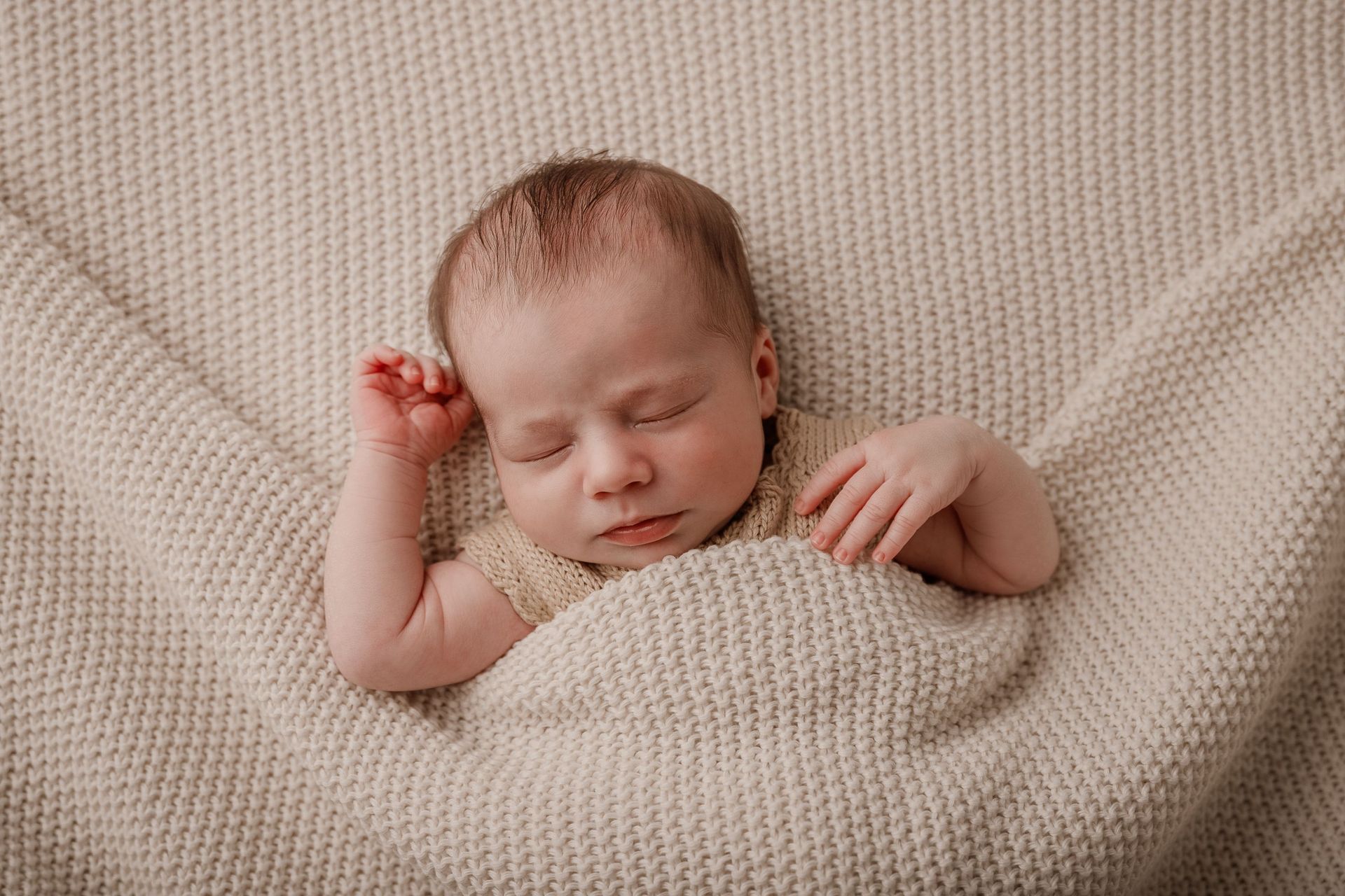 Un bebé recién nacido duerme sobre una manta blanca.