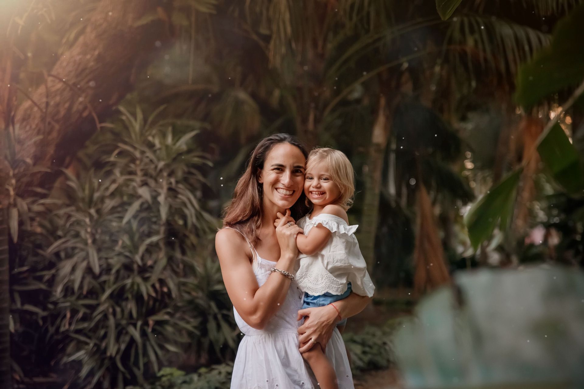 Una mujer sostiene a una niña en sus brazos en un parque.