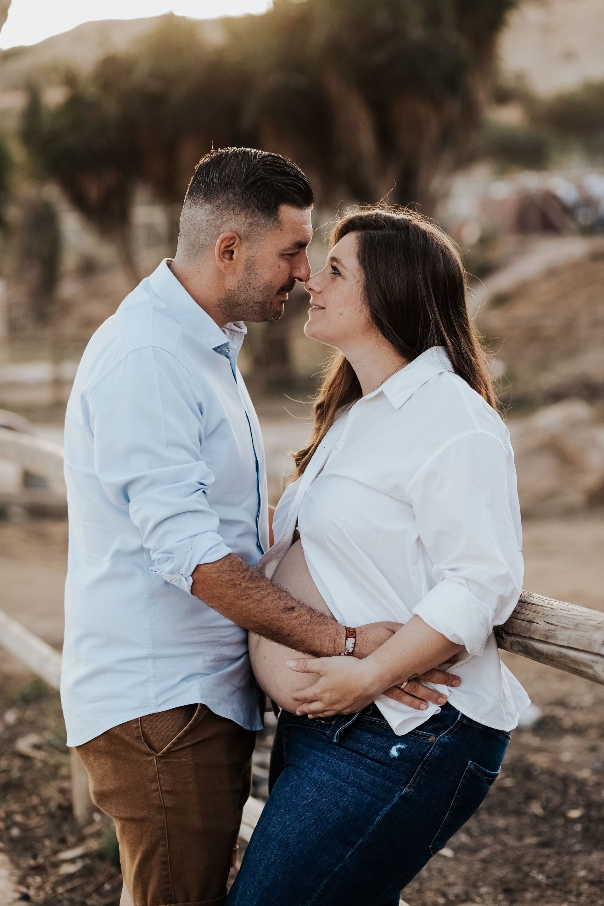 Un hombre y una mujer embarazada están parados uno al lado del otro y se besan.