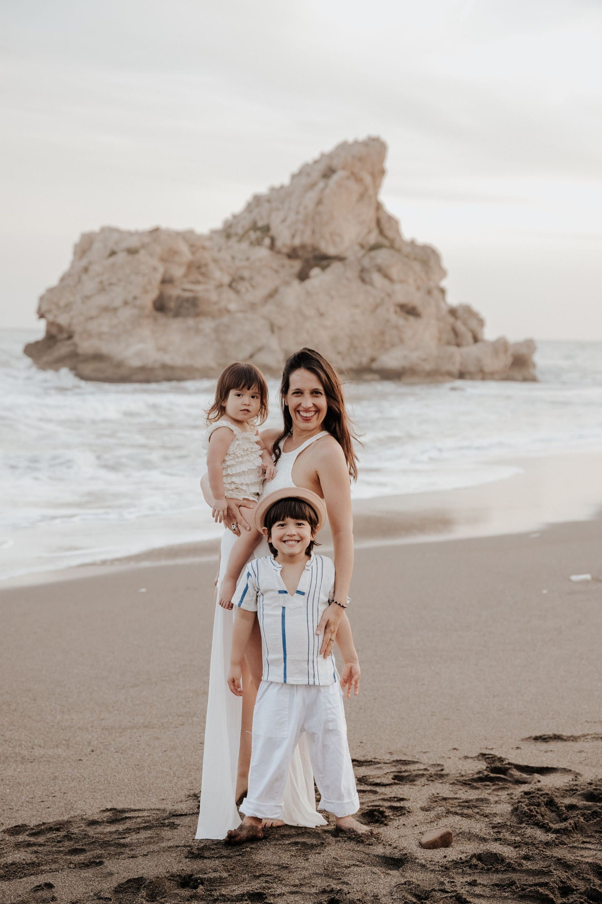 Una mujer sostiene a dos niños en la playa.