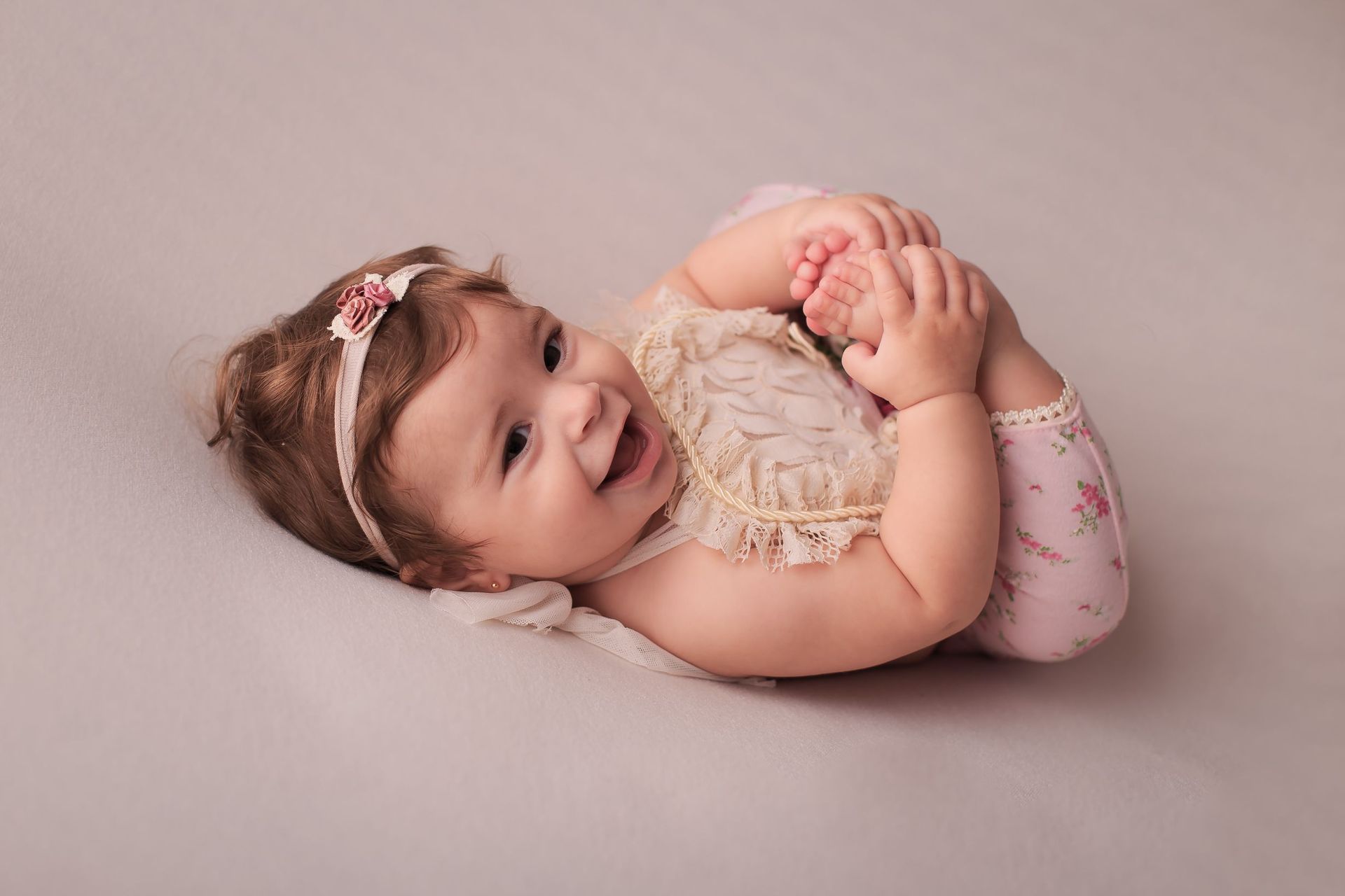 Una niña está acostada boca abajo sobre una manta y sonriendo.