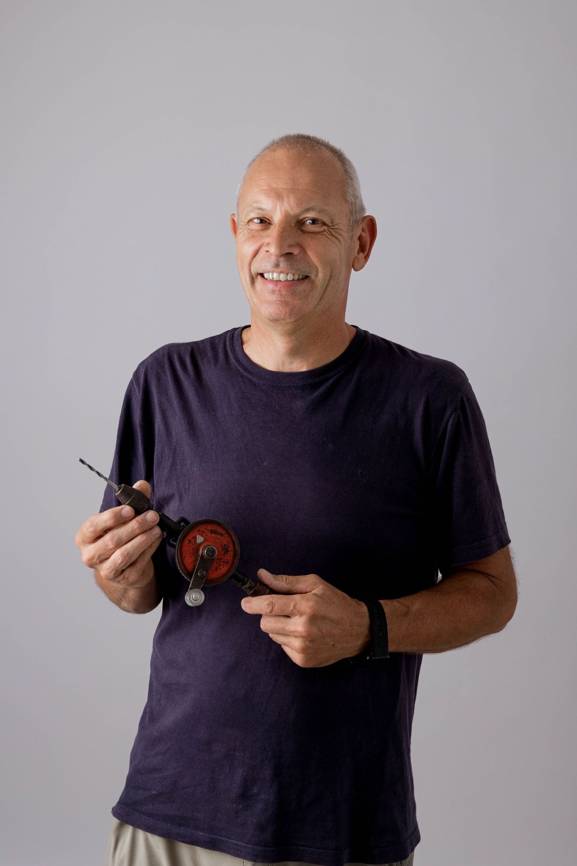 Un hombre con una camisa morada sostiene un pequeño objeto en sus manos.