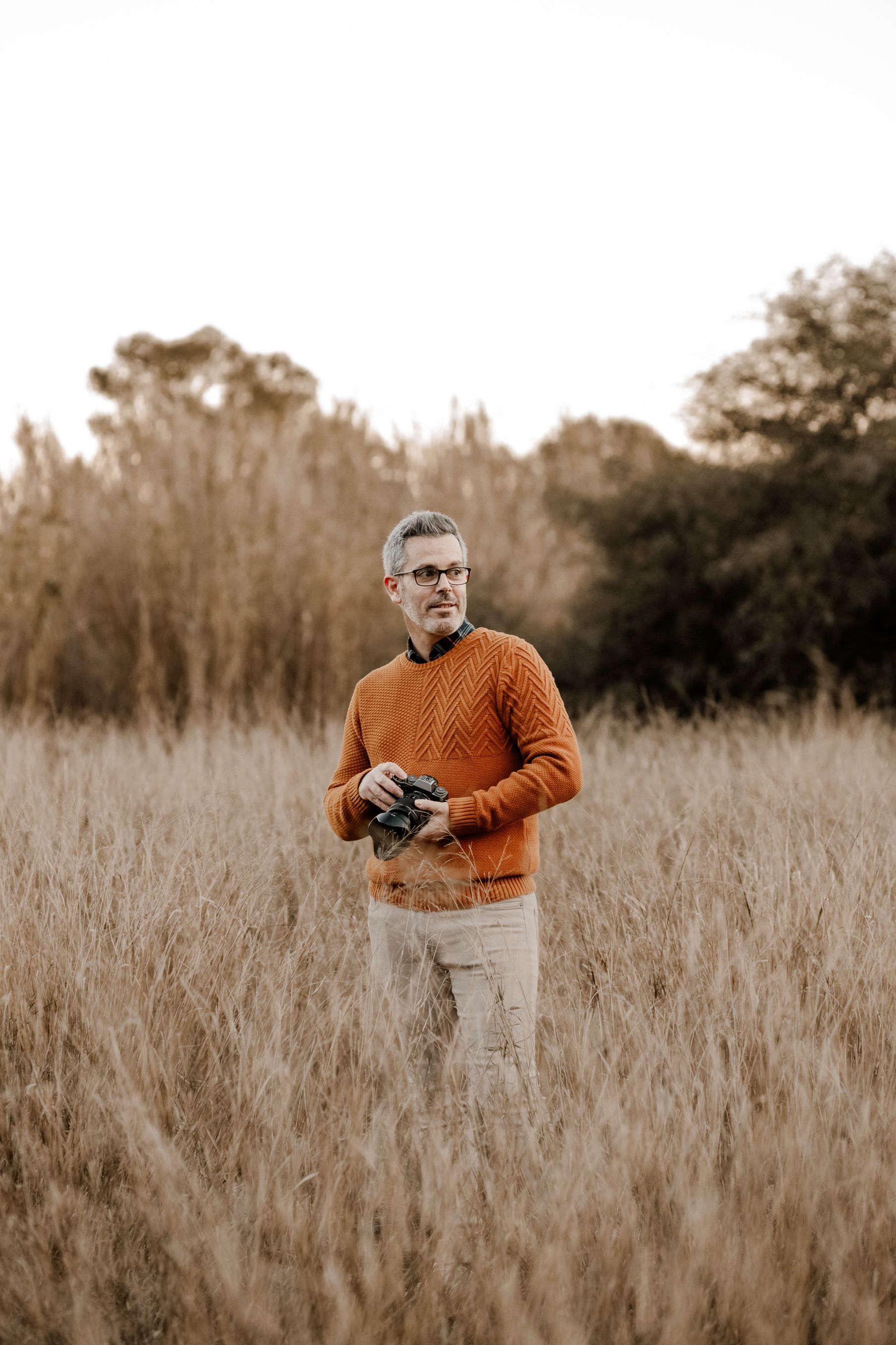 Un hombre está parado en un campo sosteniendo una cámara.