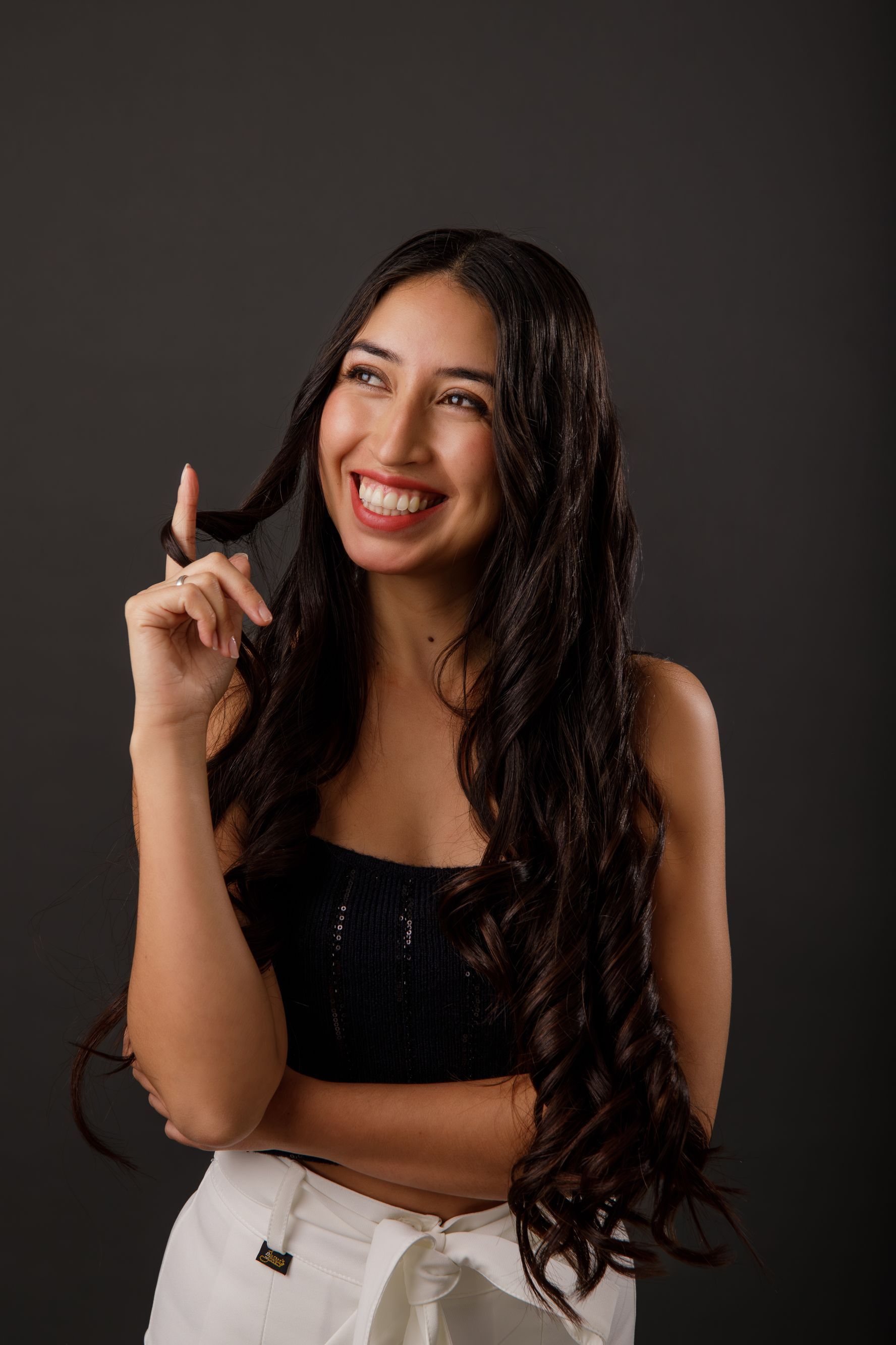 Una mujer con cabello largo sonríe y sostiene su cabello.