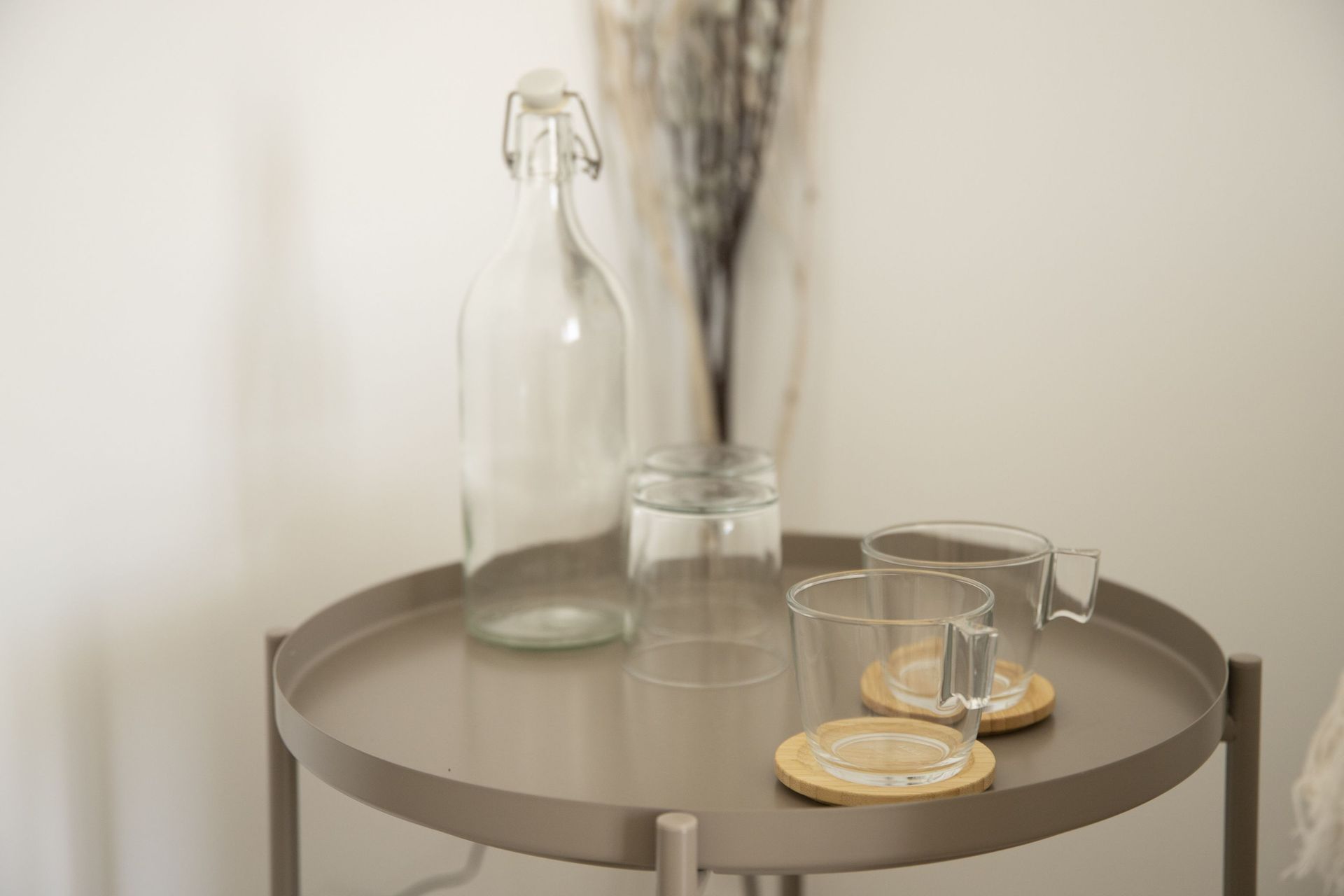 Una mesa con una botella, vasos y posavasos encima.