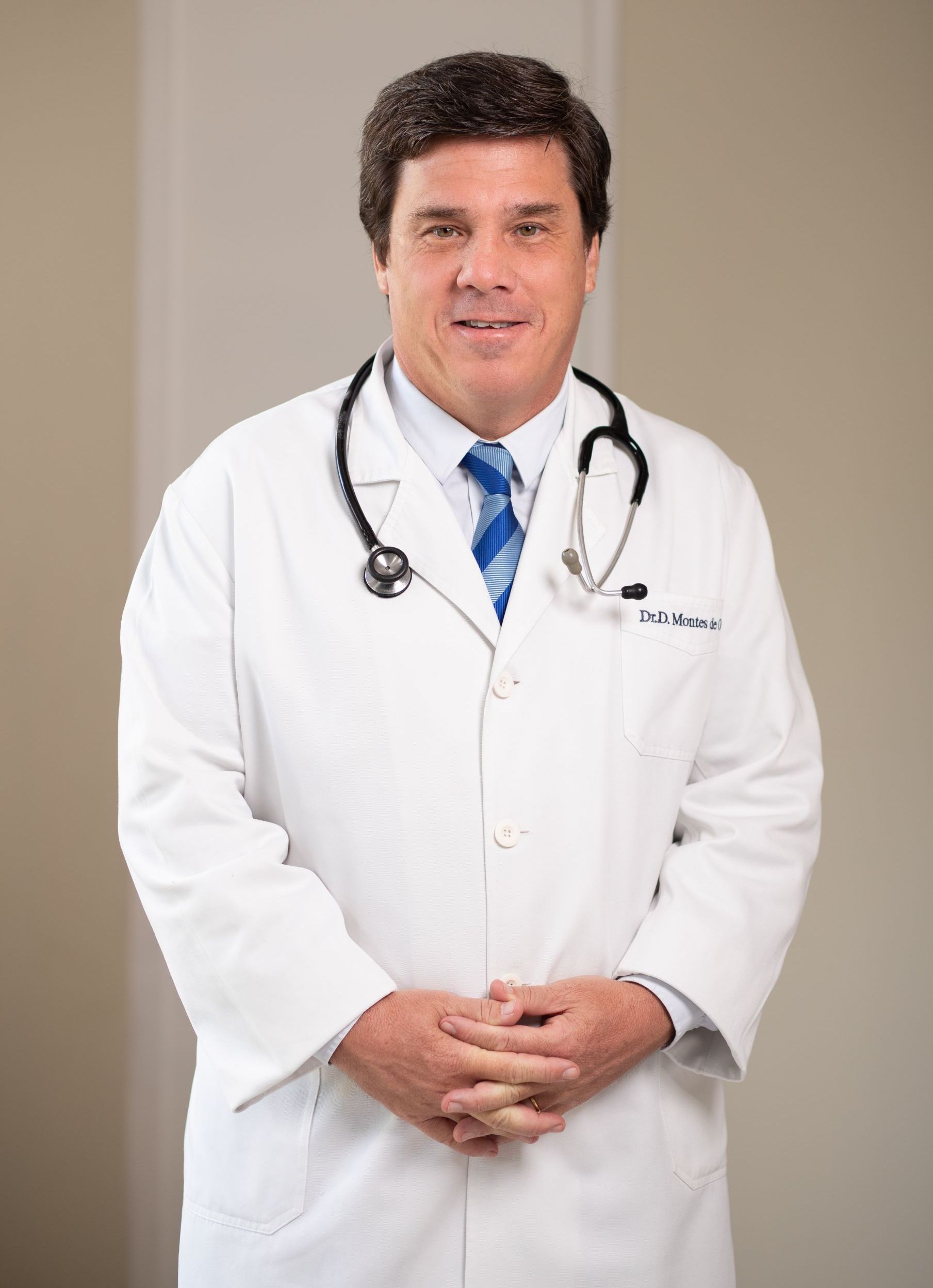 Un médico que lleva una bata blanca y corbata y un estetoscopio alrededor del cuello.