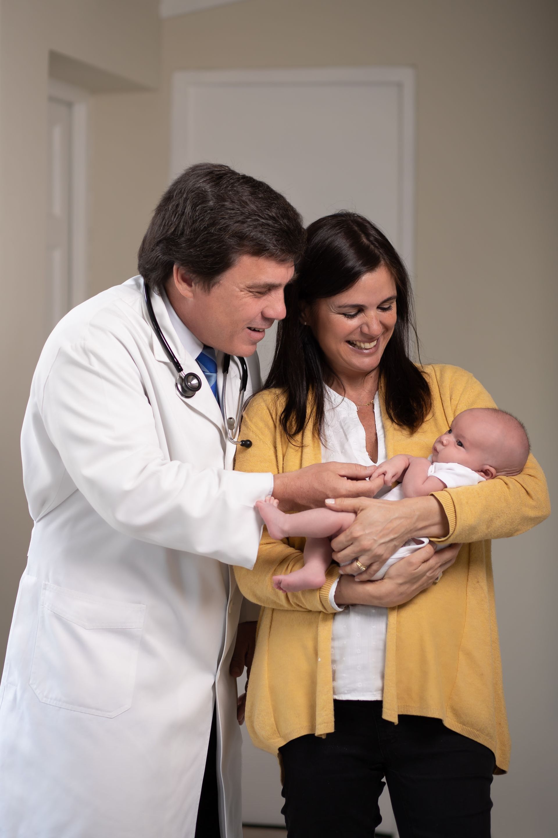 Un médico está examinando a un bebé mientras una mujer lo sostiene.
