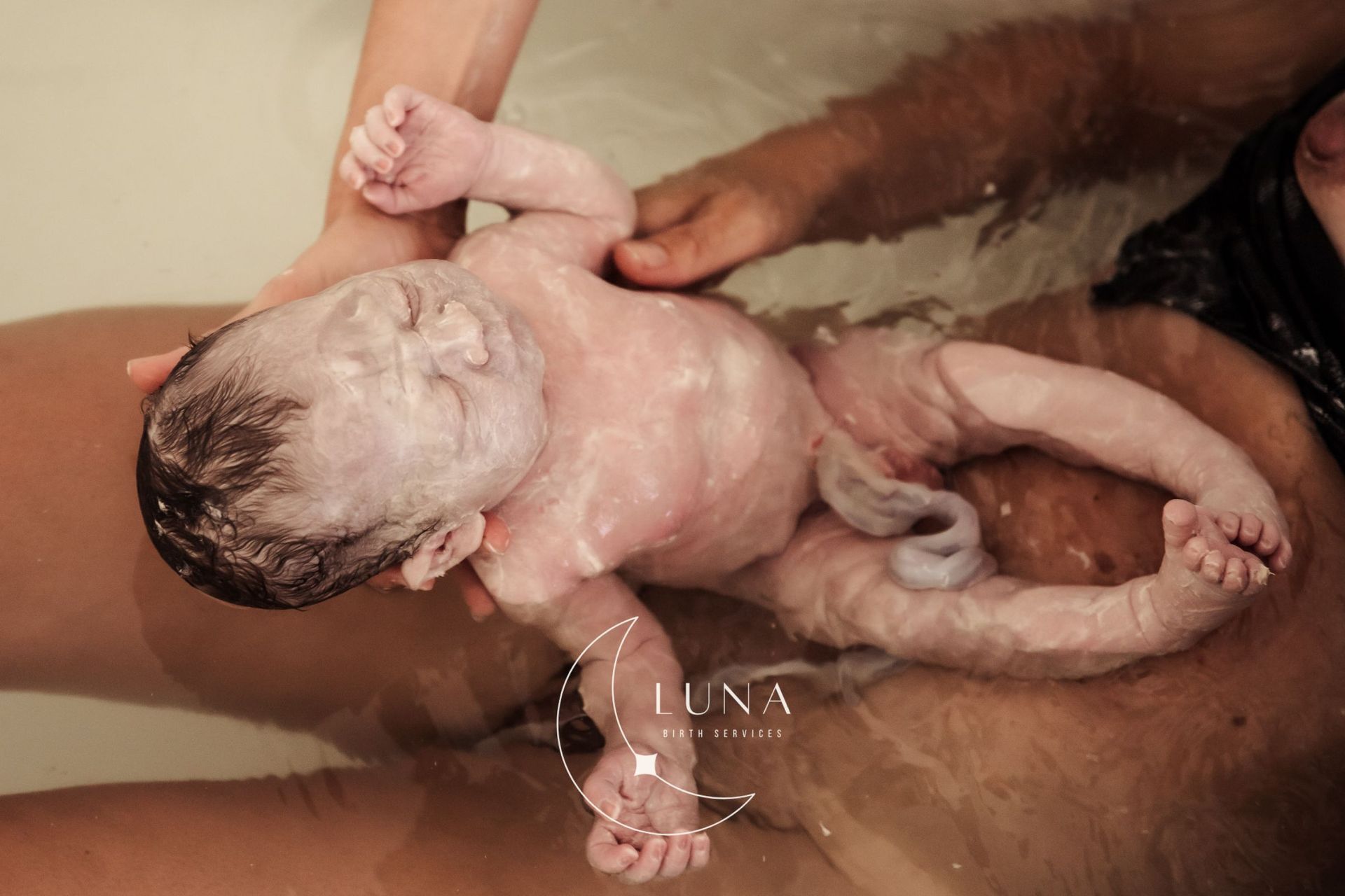 Una mujer sostiene a un bebé recién nacido en una bañera.