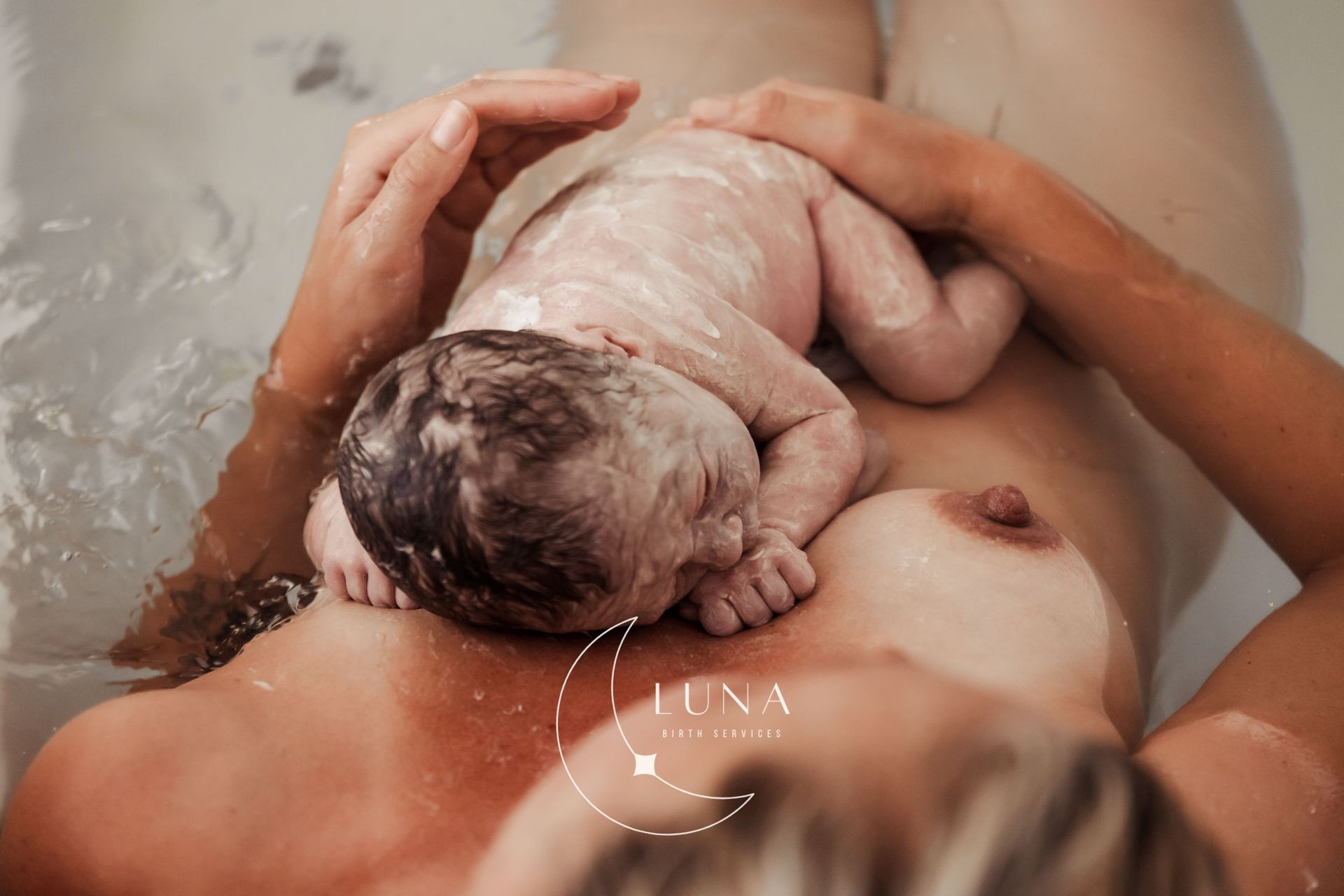 Una mujer sostiene en sus brazos a un bebé recién nacido en una bañera.