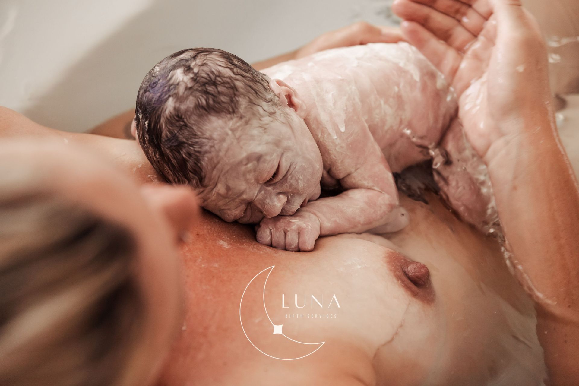 Una mujer sostiene a un bebé recién nacido en una bañera.