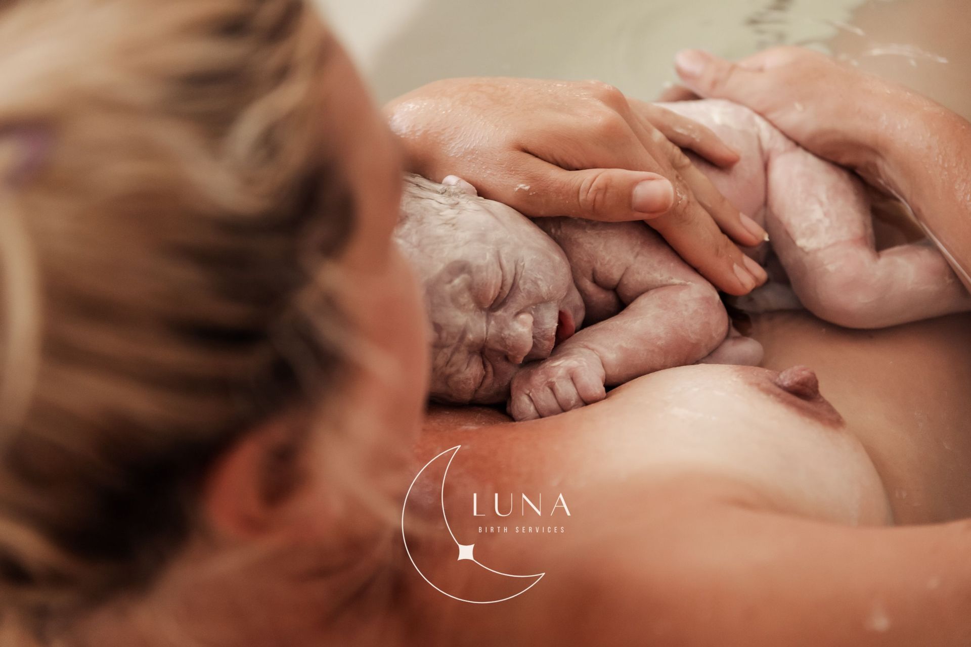 Una mujer sostiene en sus brazos a un bebé recién nacido en una bañera.