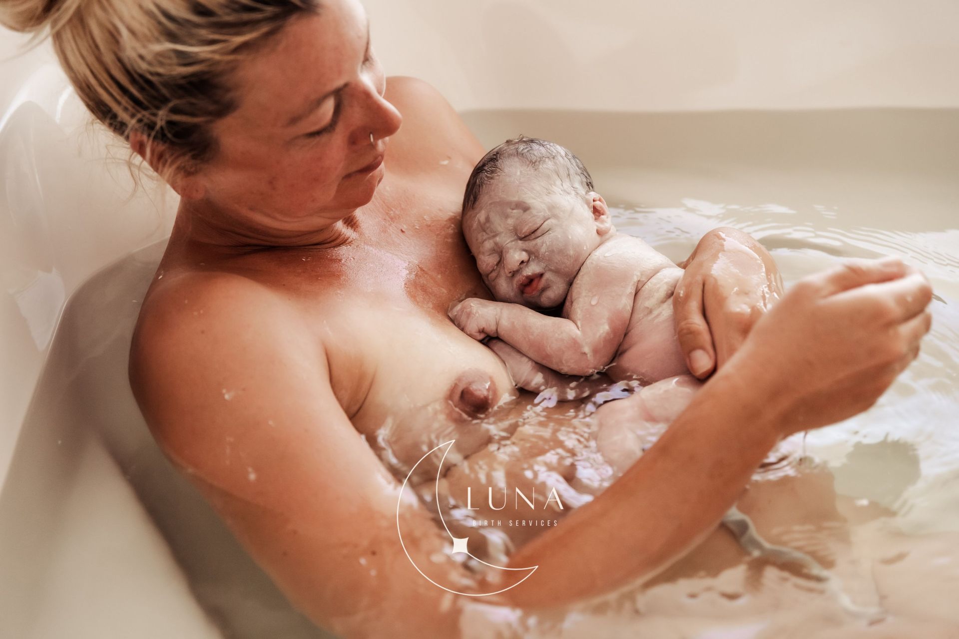 Una mujer sostiene a un bebé recién nacido en una bañera.