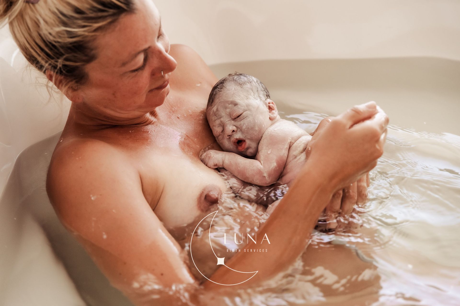 Una mujer sostiene a un bebé recién nacido en una bañera.