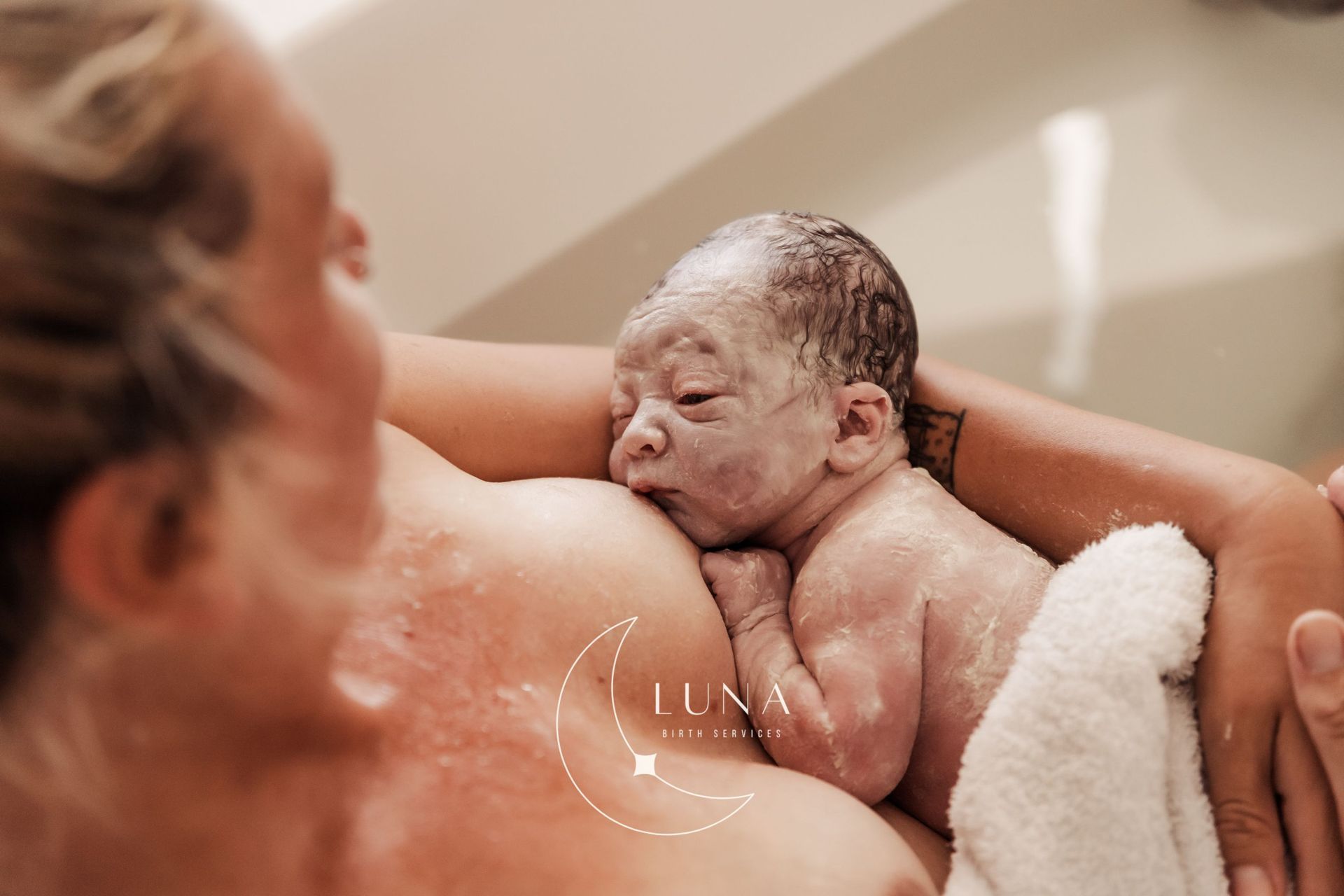 Una mujer sostiene en sus brazos a un bebé recién nacido en una bañera.