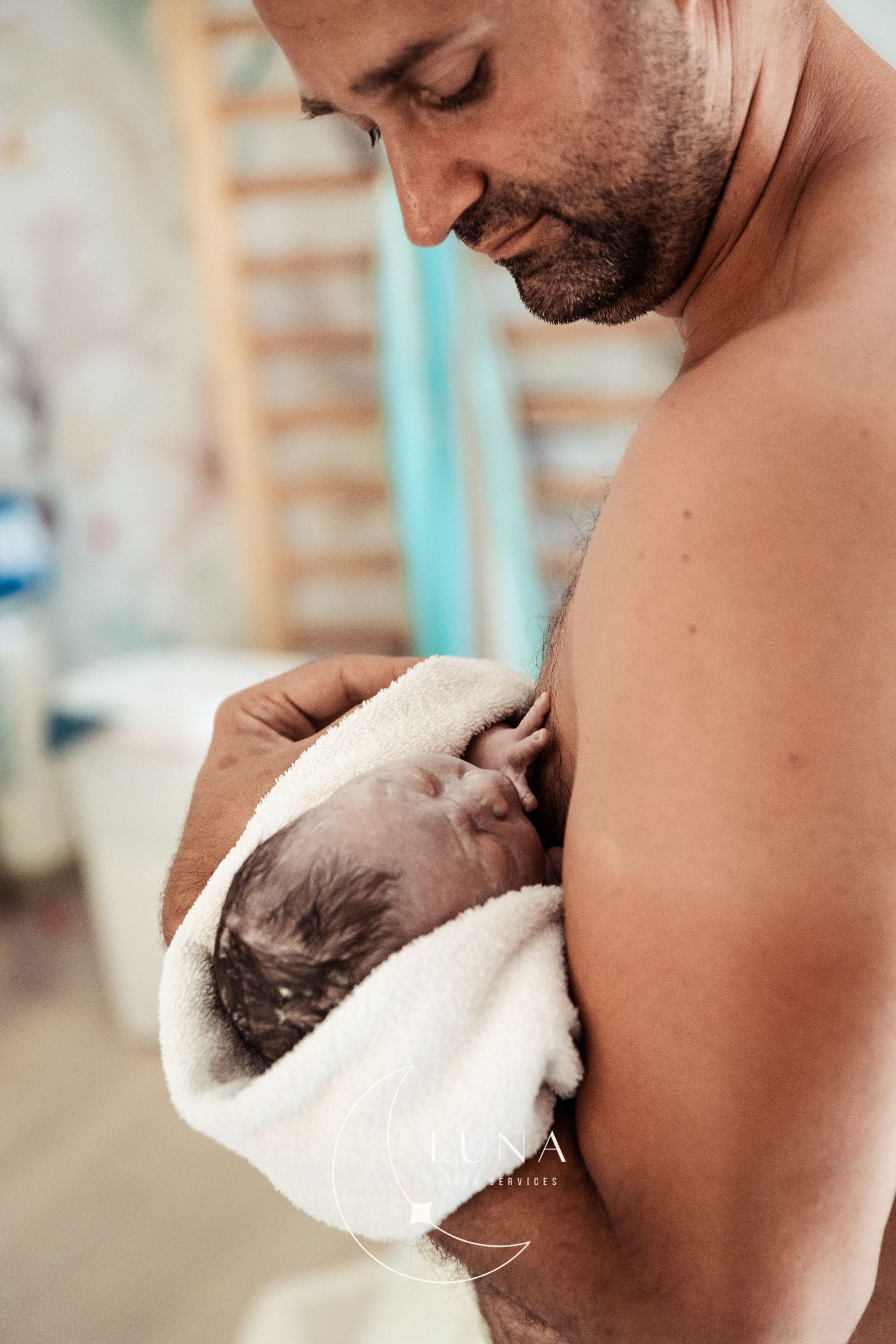 Un hombre sostiene a un bebé recién nacido envuelto en una toalla.
