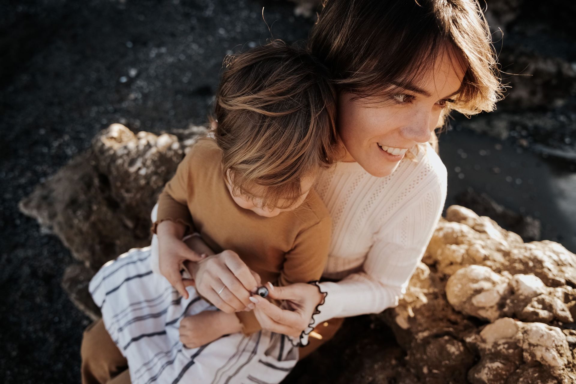 Una mujer está sentada en una roca sosteniendo un bebé.