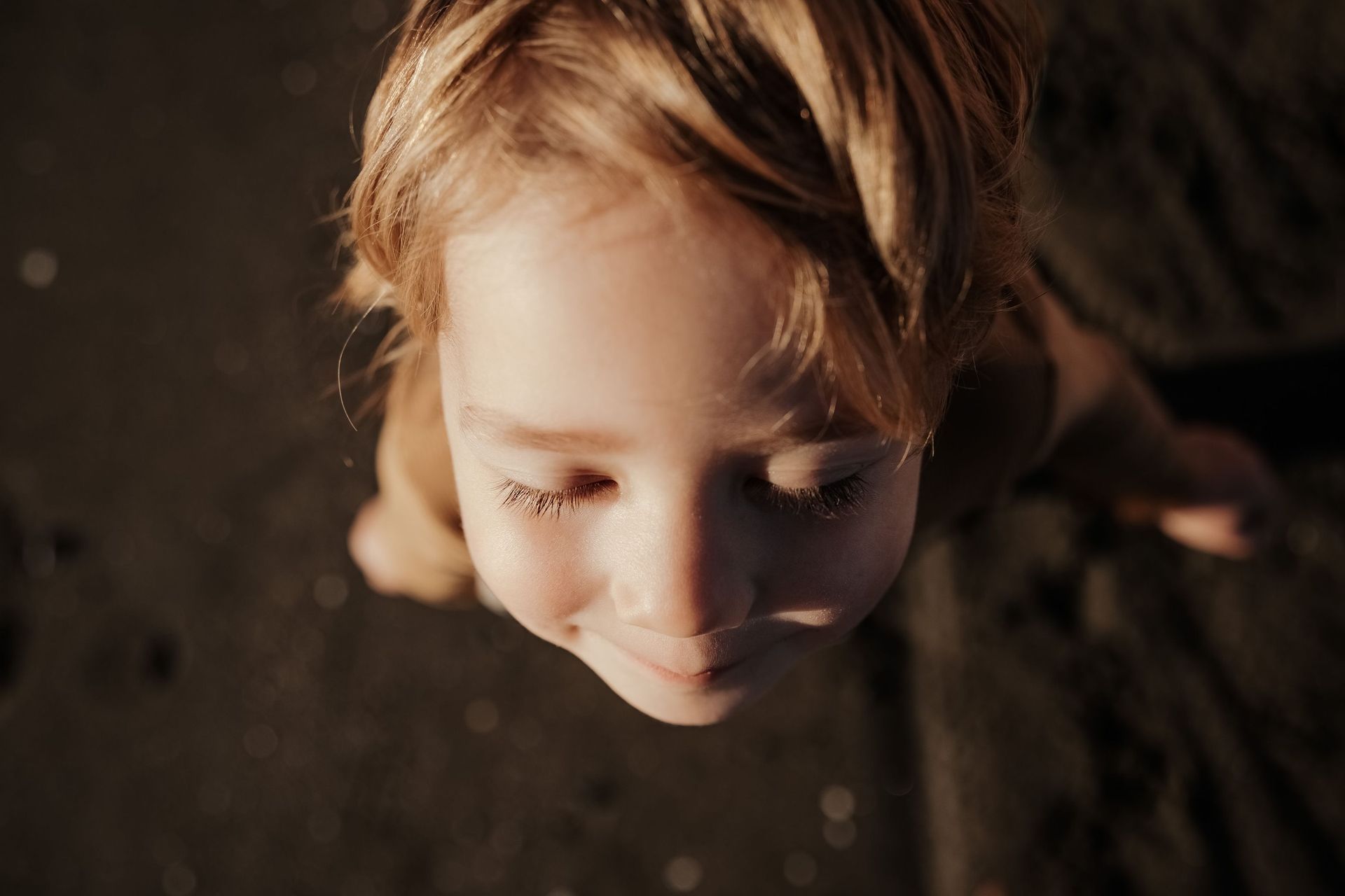 Una niña mira a la cámara mientras está acostada en la playa.