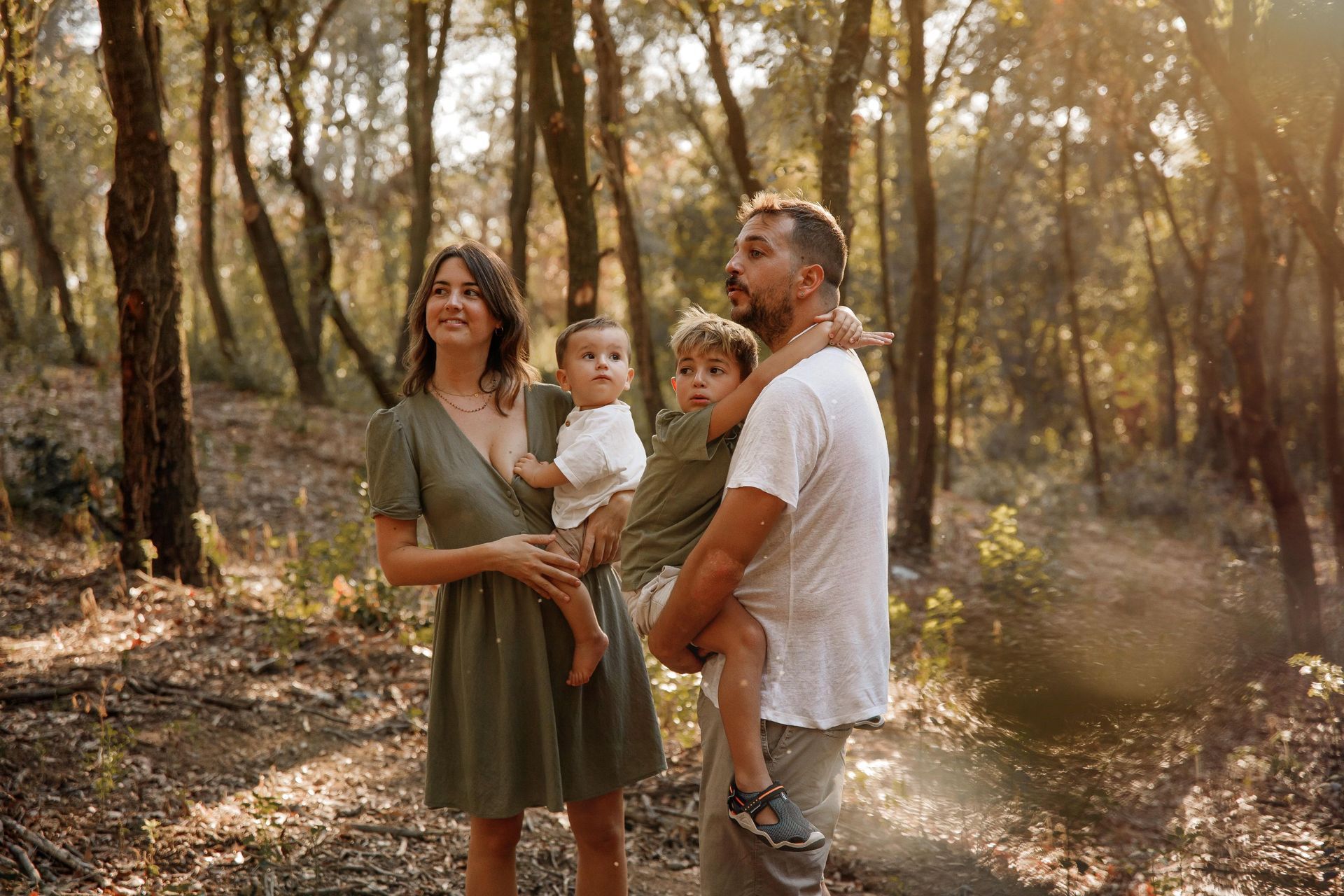 Una familia está parada en el bosque sosteniendo a dos niños.