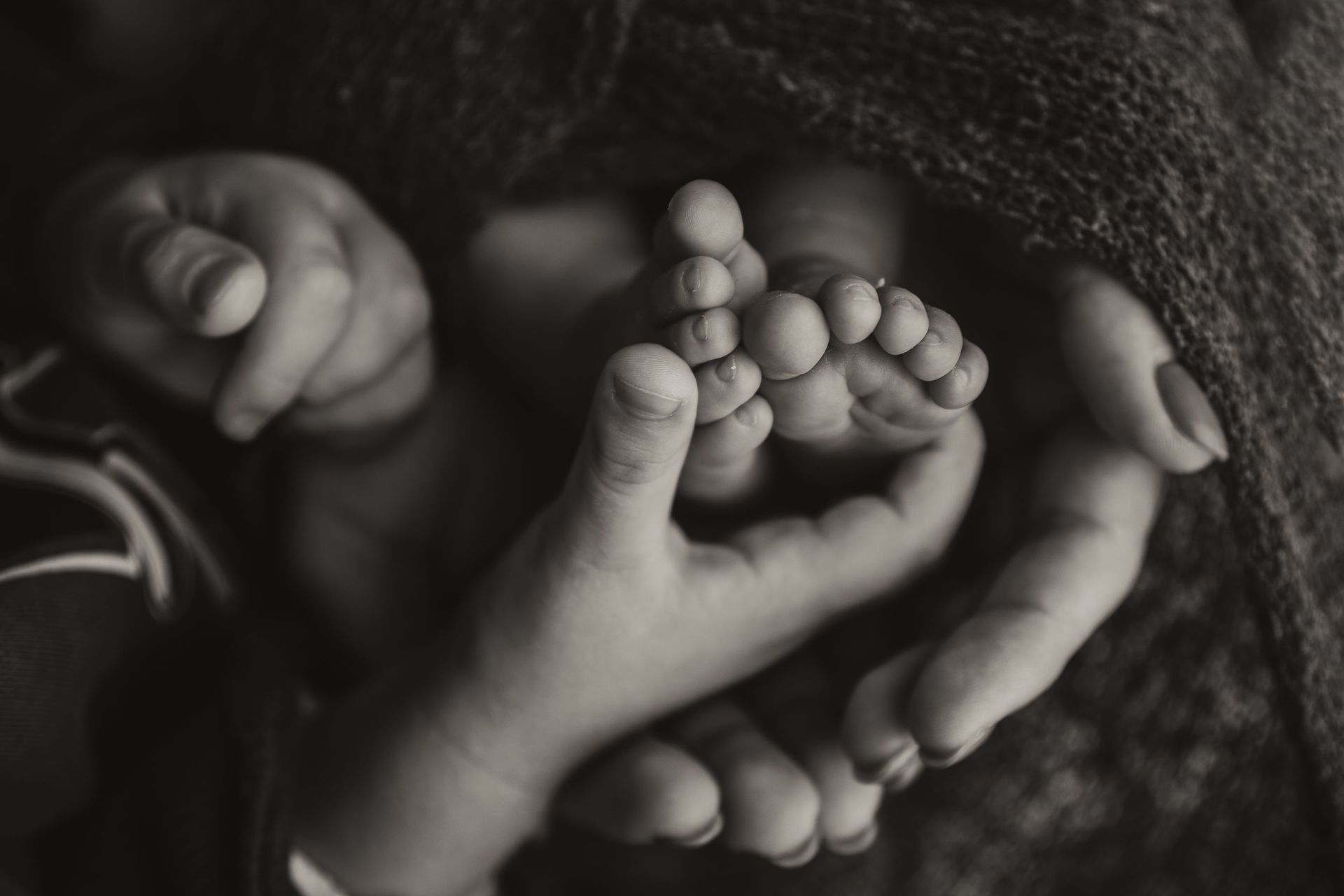 Una mujer sostiene los pies de un bebé en sus manos en una fotografía en blanco y negro.