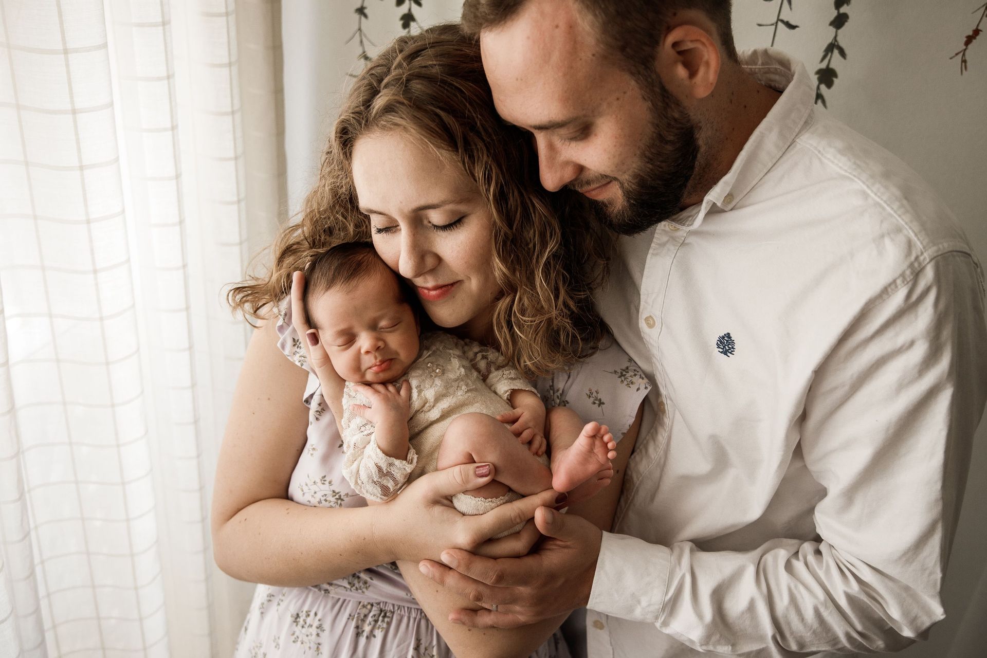 Un hombre y una mujer sostienen un bebé recién nacido en sus brazos.