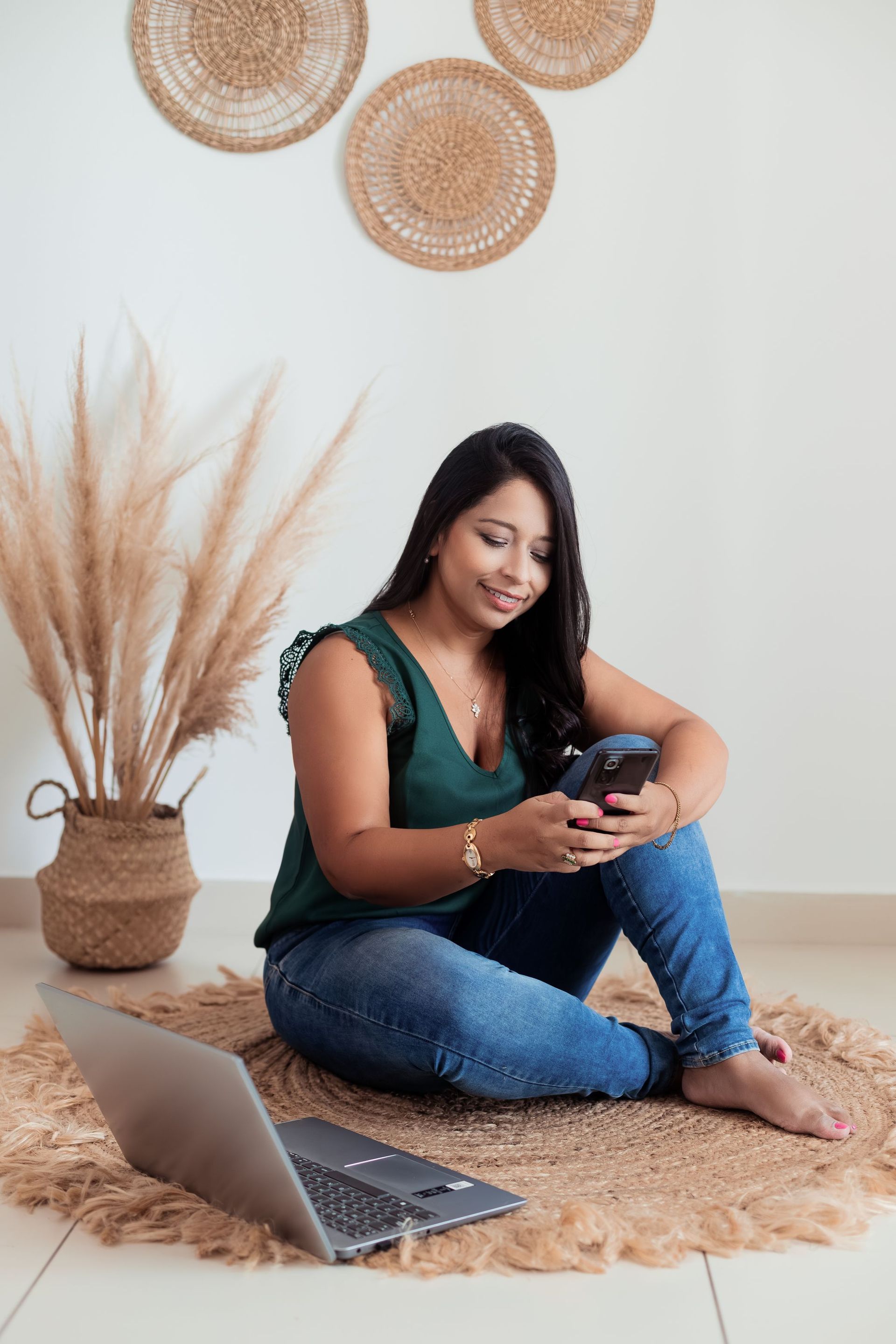 Una mujer está sentada en el suelo mirando su teléfono celular.