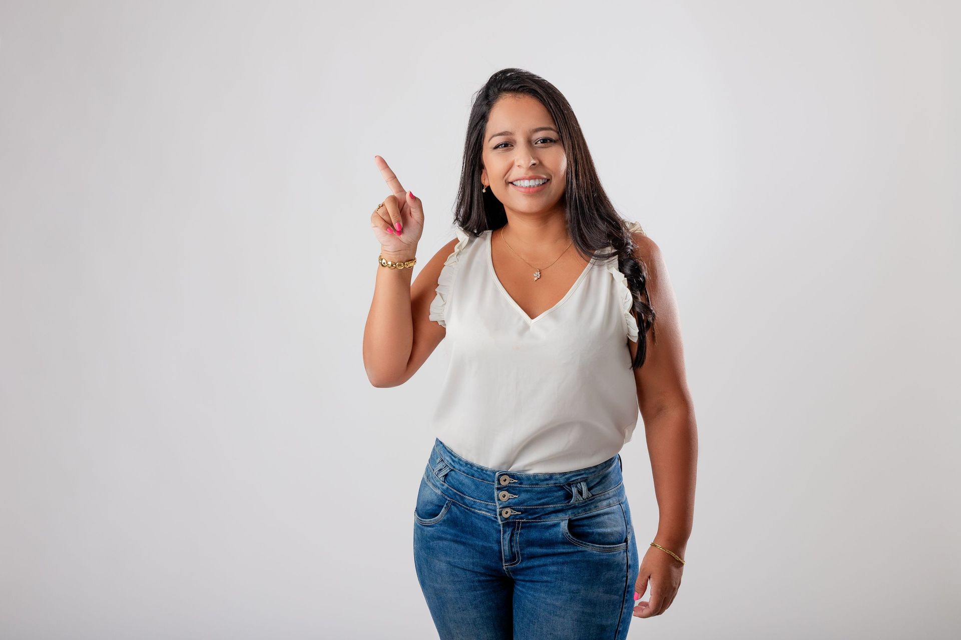Una mujer con una camiseta blanca y pantalones vaqueros azules señala hacia arriba.