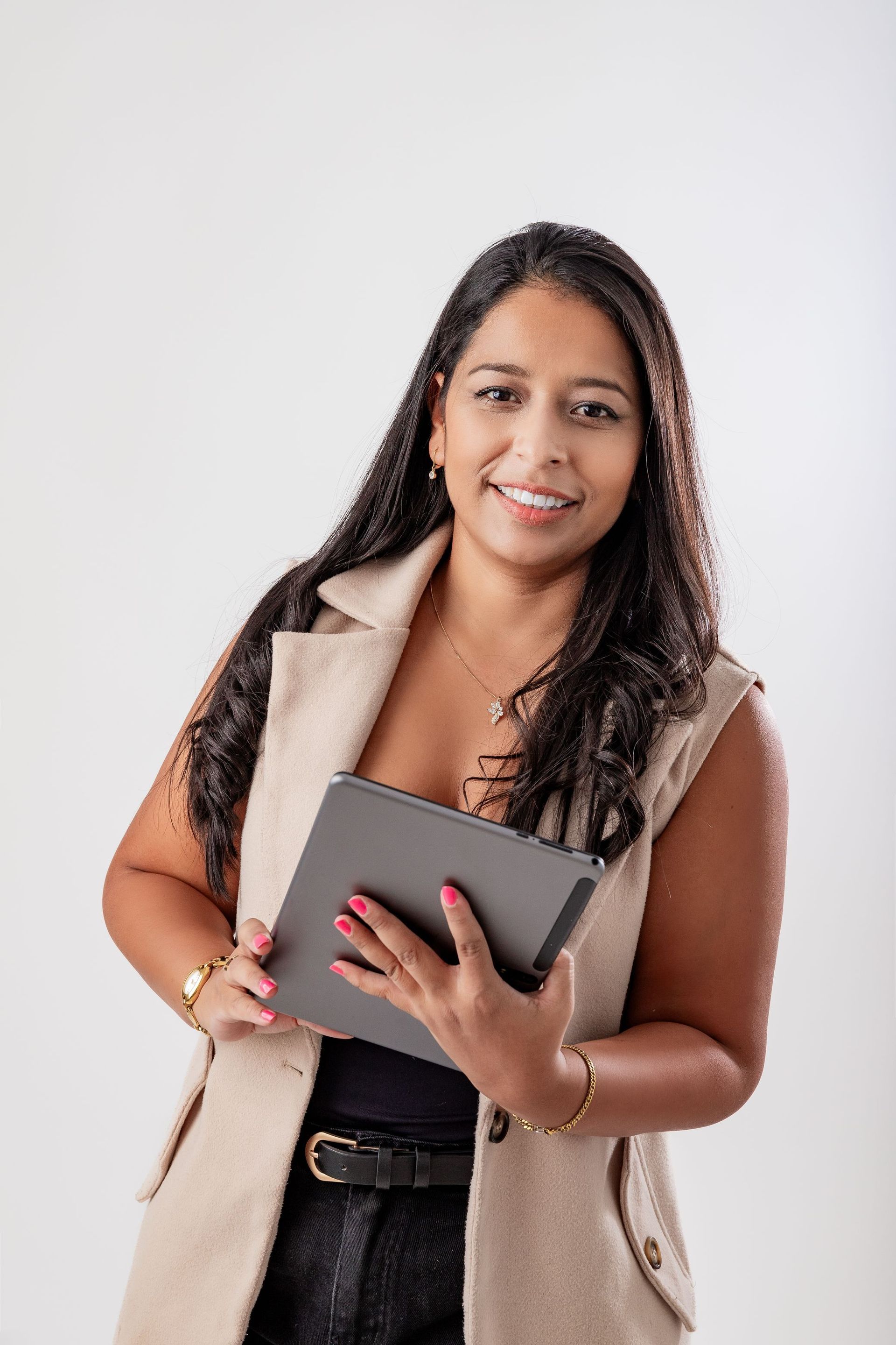 Una mujer sostiene una tableta en sus manos y sonríe.