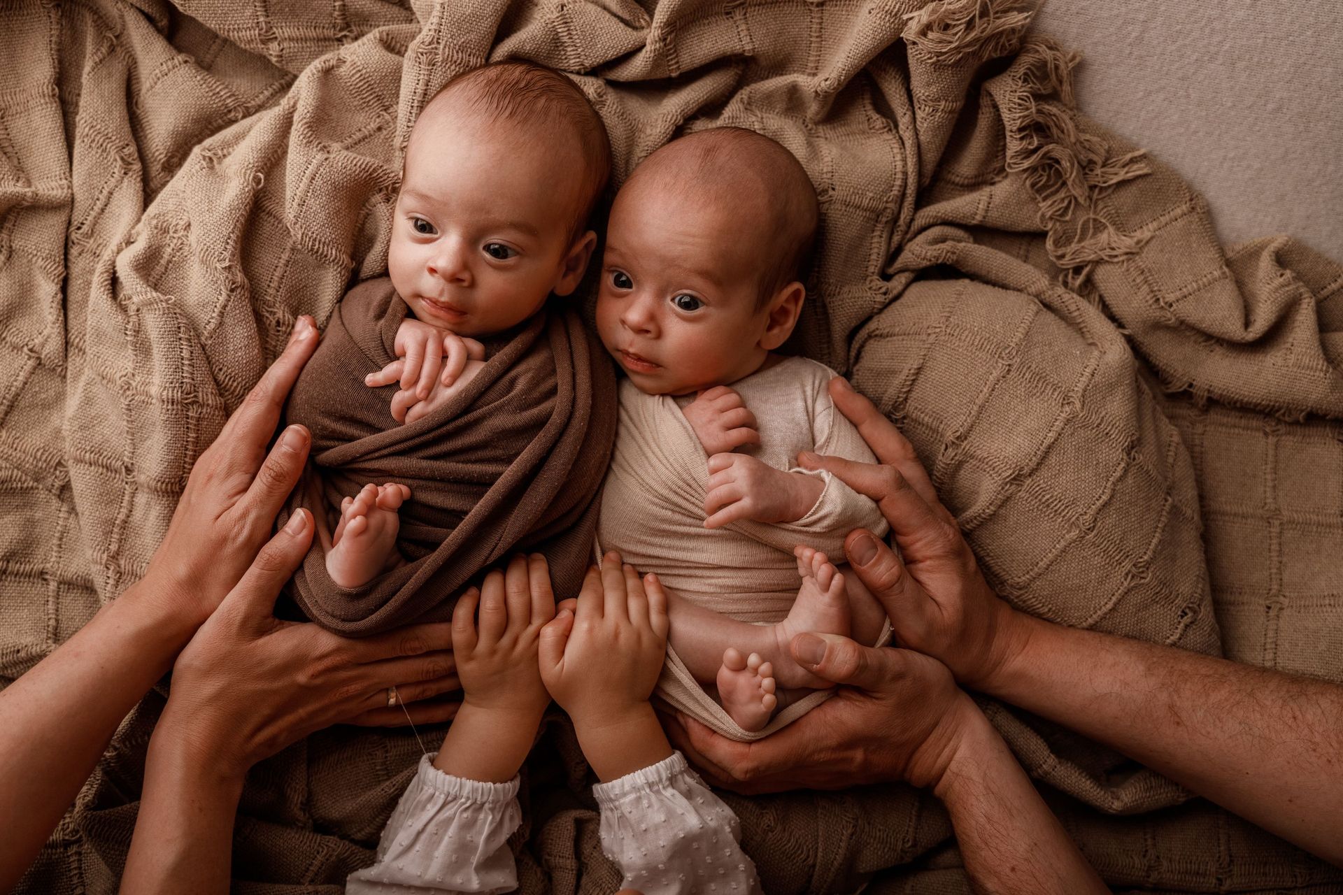 Un grupo de personas sostiene dos bebés recién nacidos en sus manos.