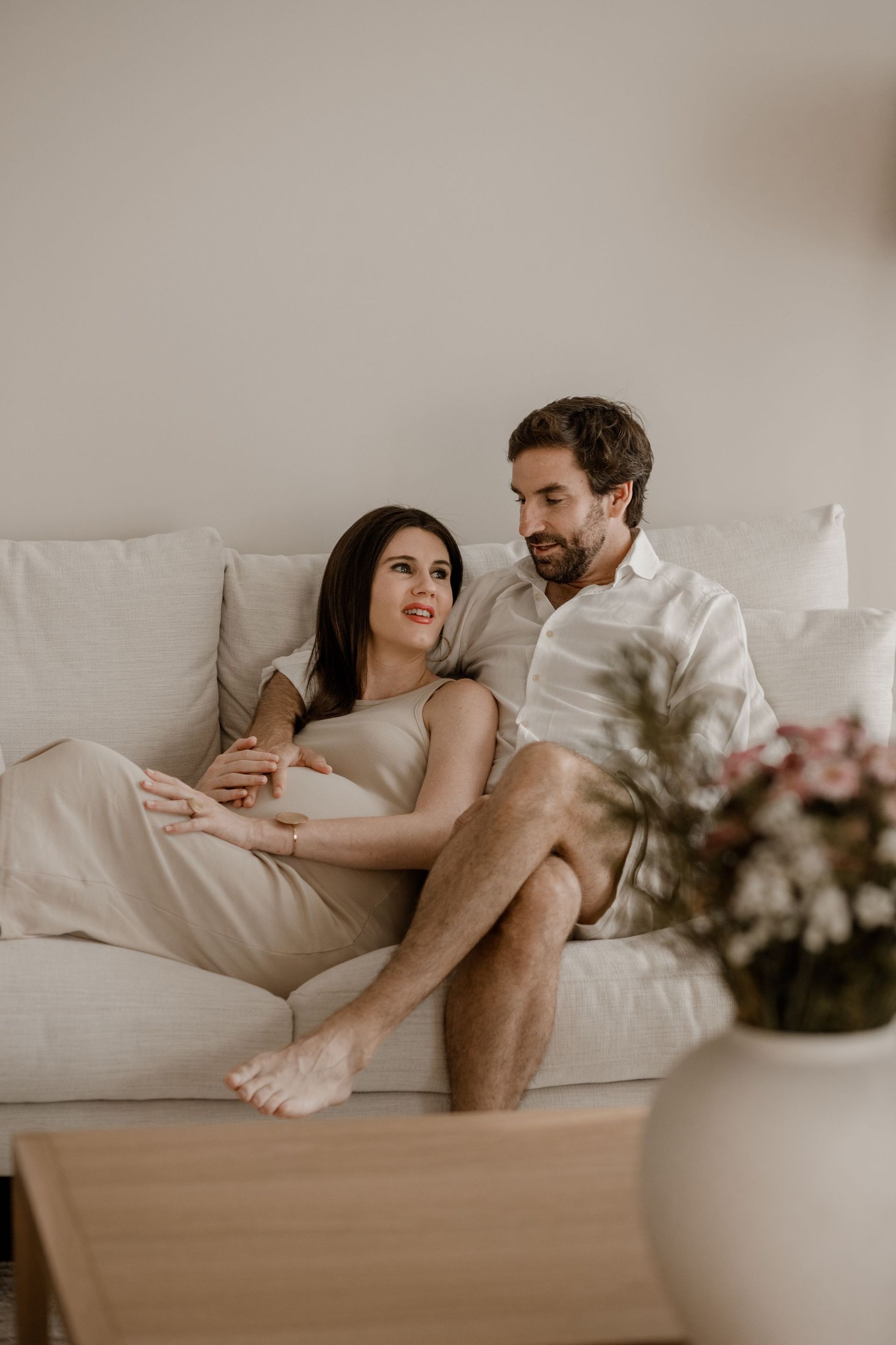 Un hombre y una mujer embarazada están sentados en un sofá.