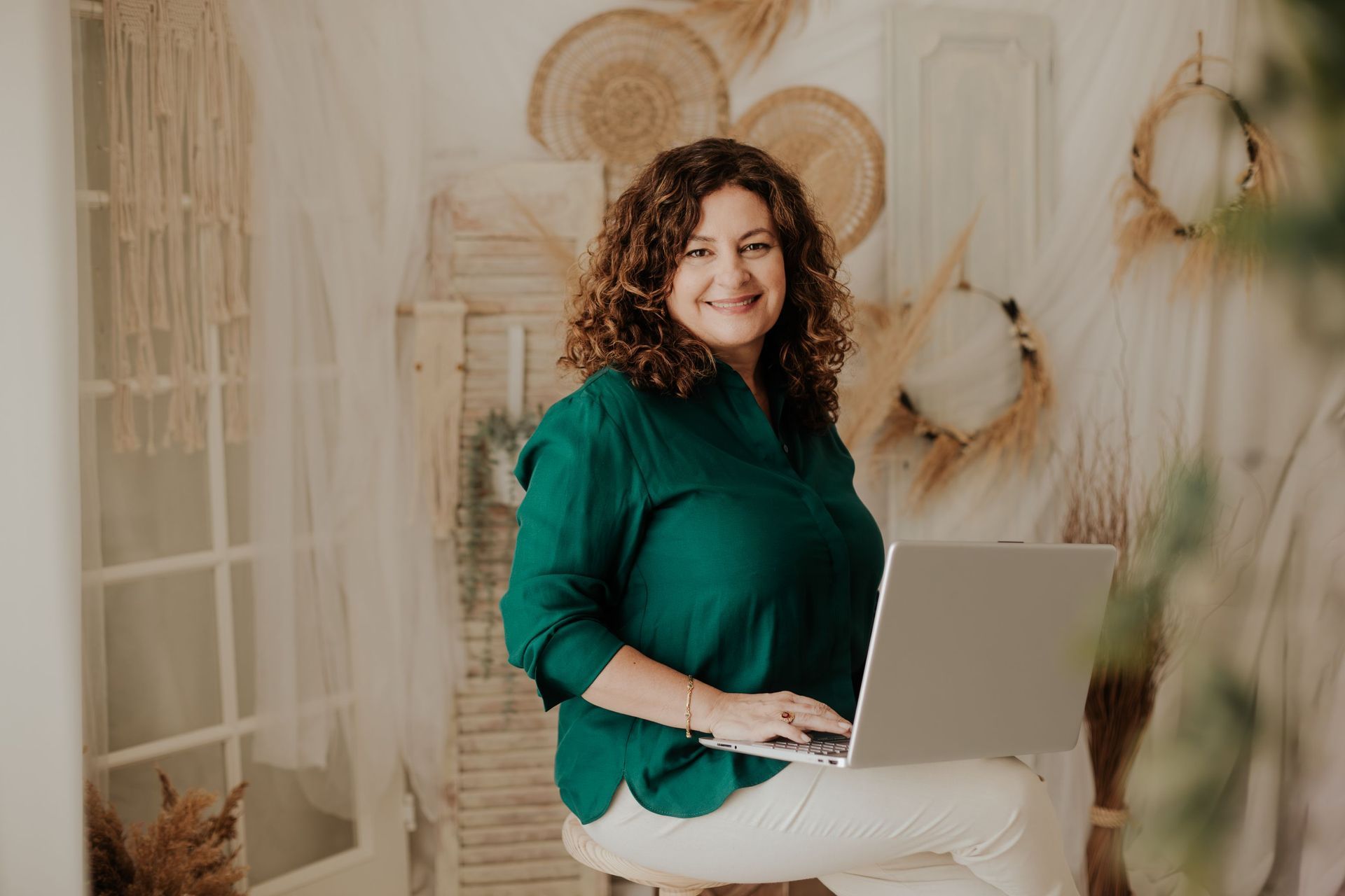 Una mujer está sentada en un taburete usando una computadora portátil.