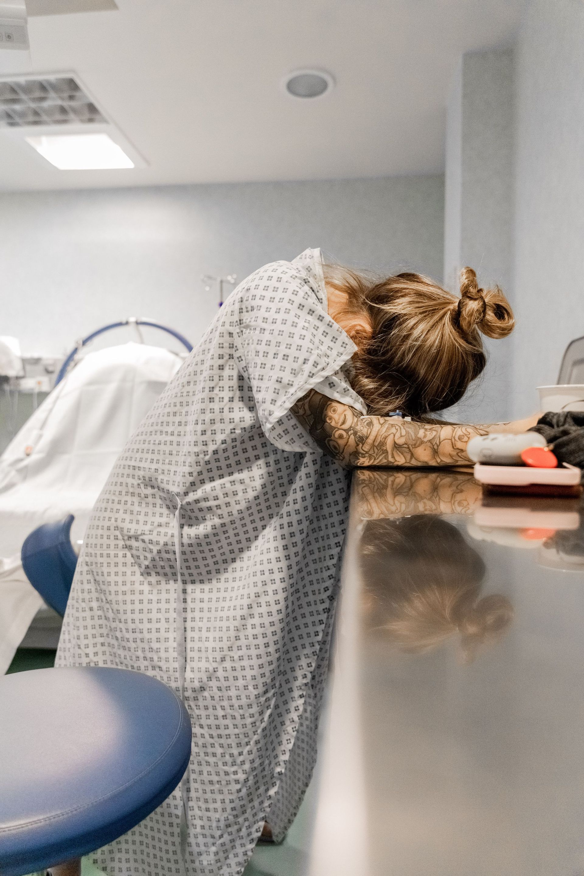 Una mujer vestida con una bata de hospital está apoyada sobre un mostrador.