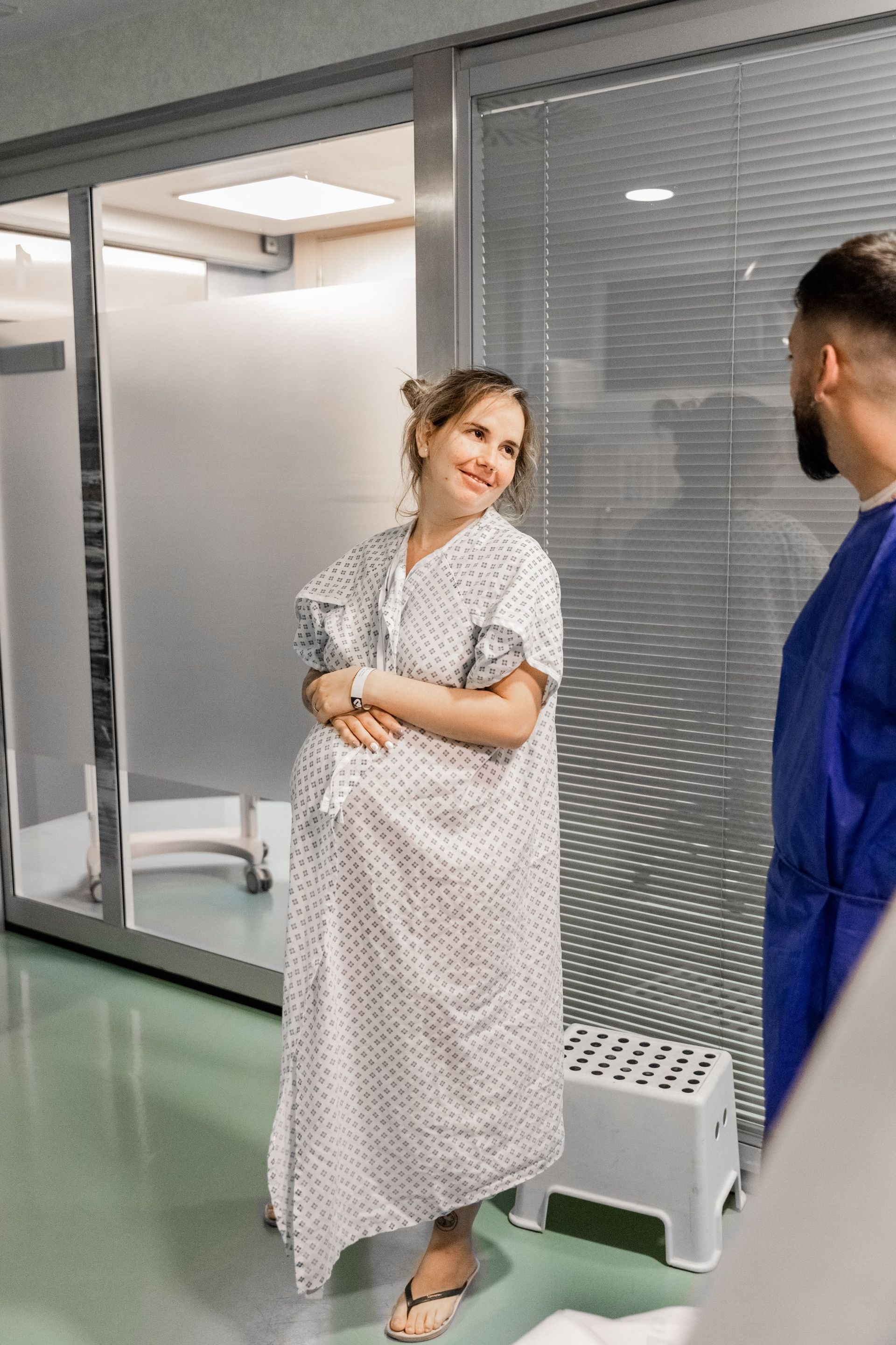 Una mujer embarazada con una bata de hospital está de pie junto a un hombre con una bata de laboratorio.