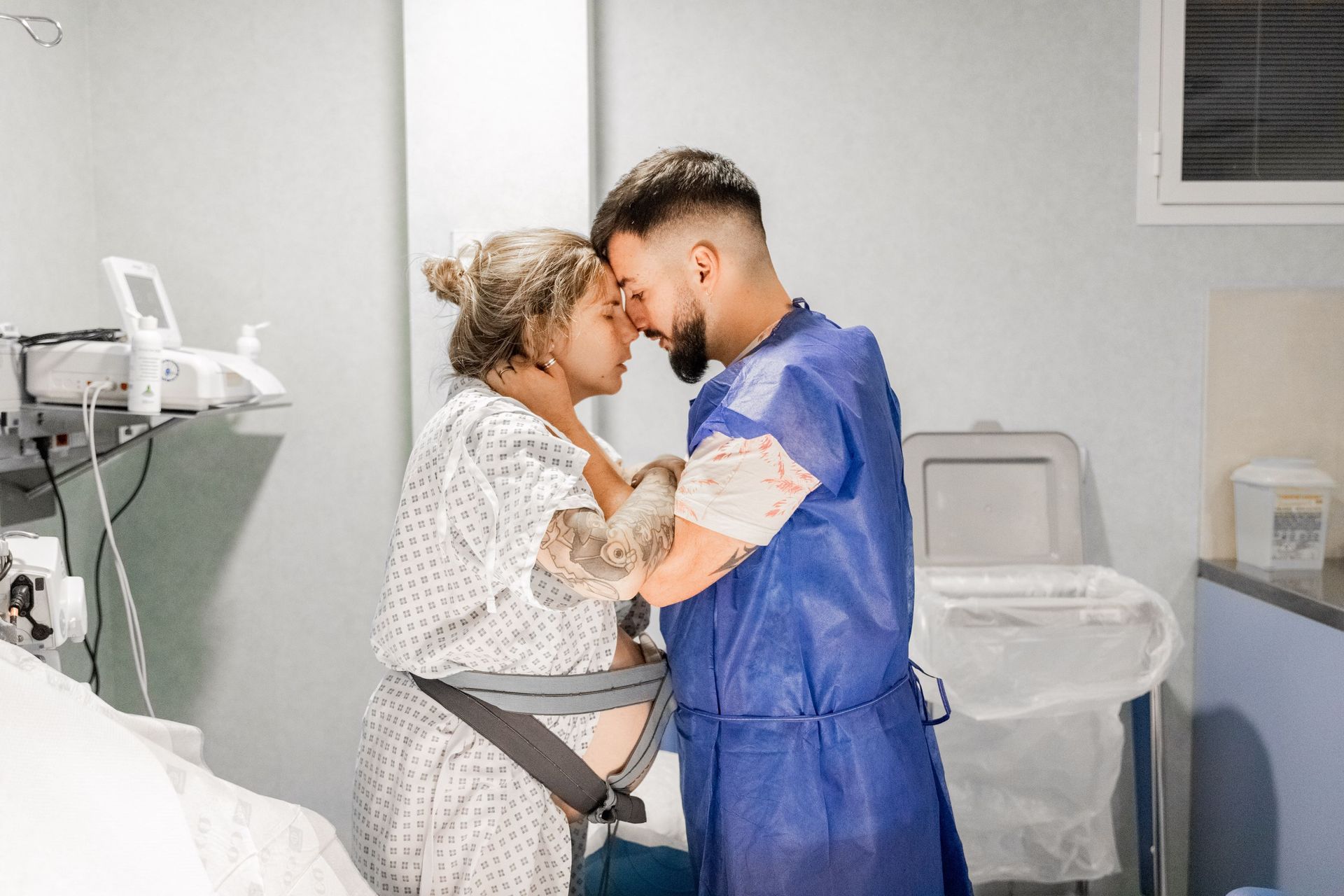 Un hombre y una mujer embarazada están parados uno al lado del otro en una habitación de hospital.