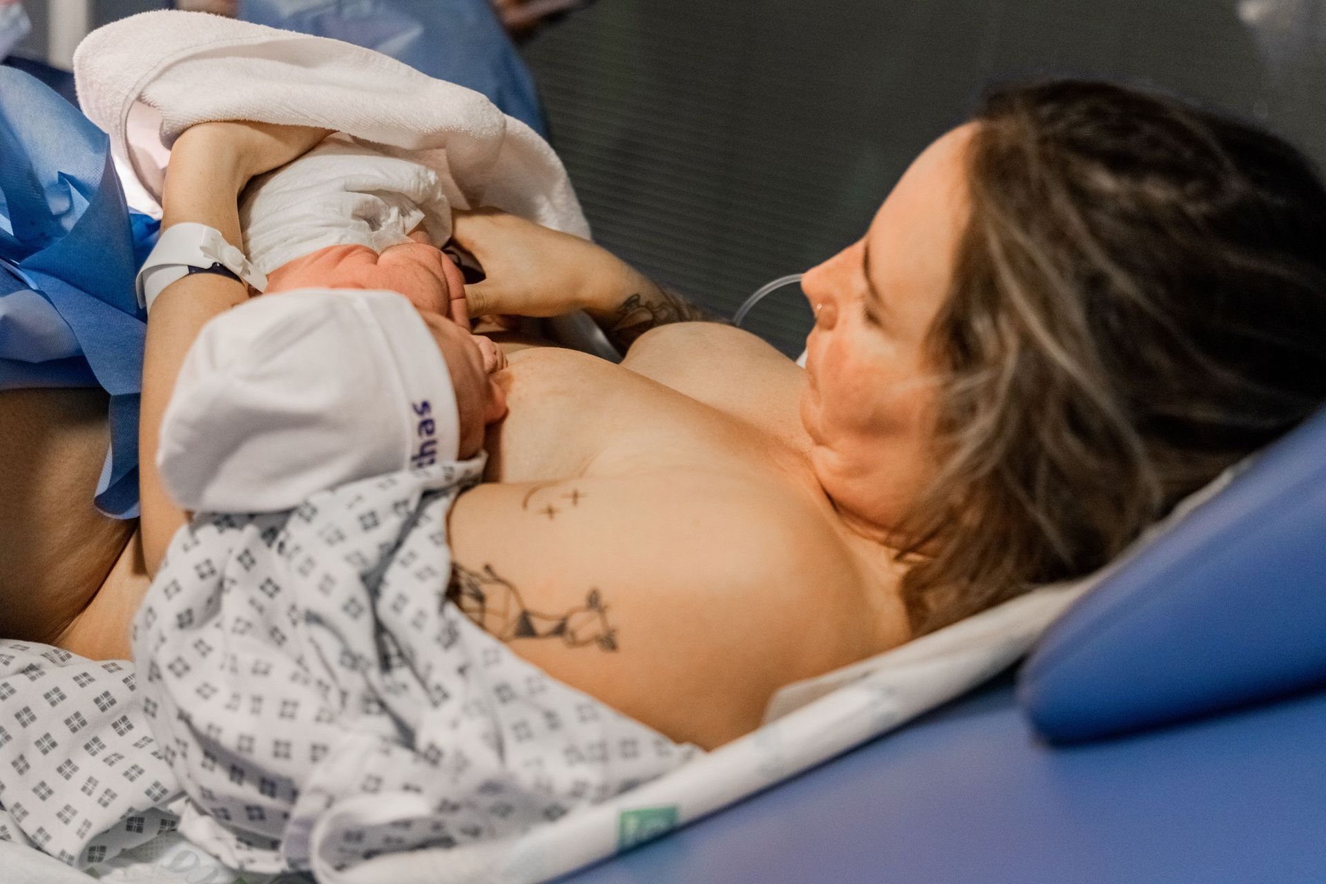 Una mujer está amamantando a un bebé recién nacido en una cama de hospital.