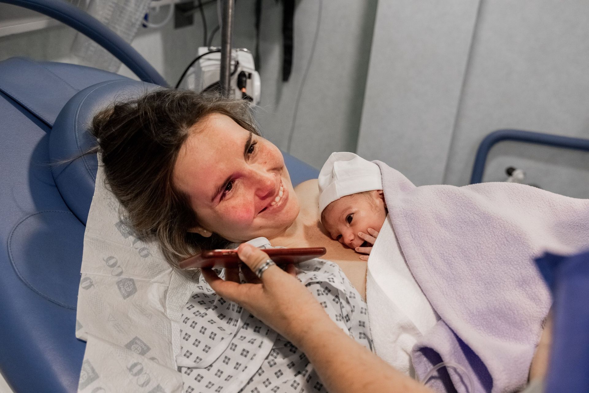 una mujer está acostada en una cama de hospital con un bebé recién nacido .