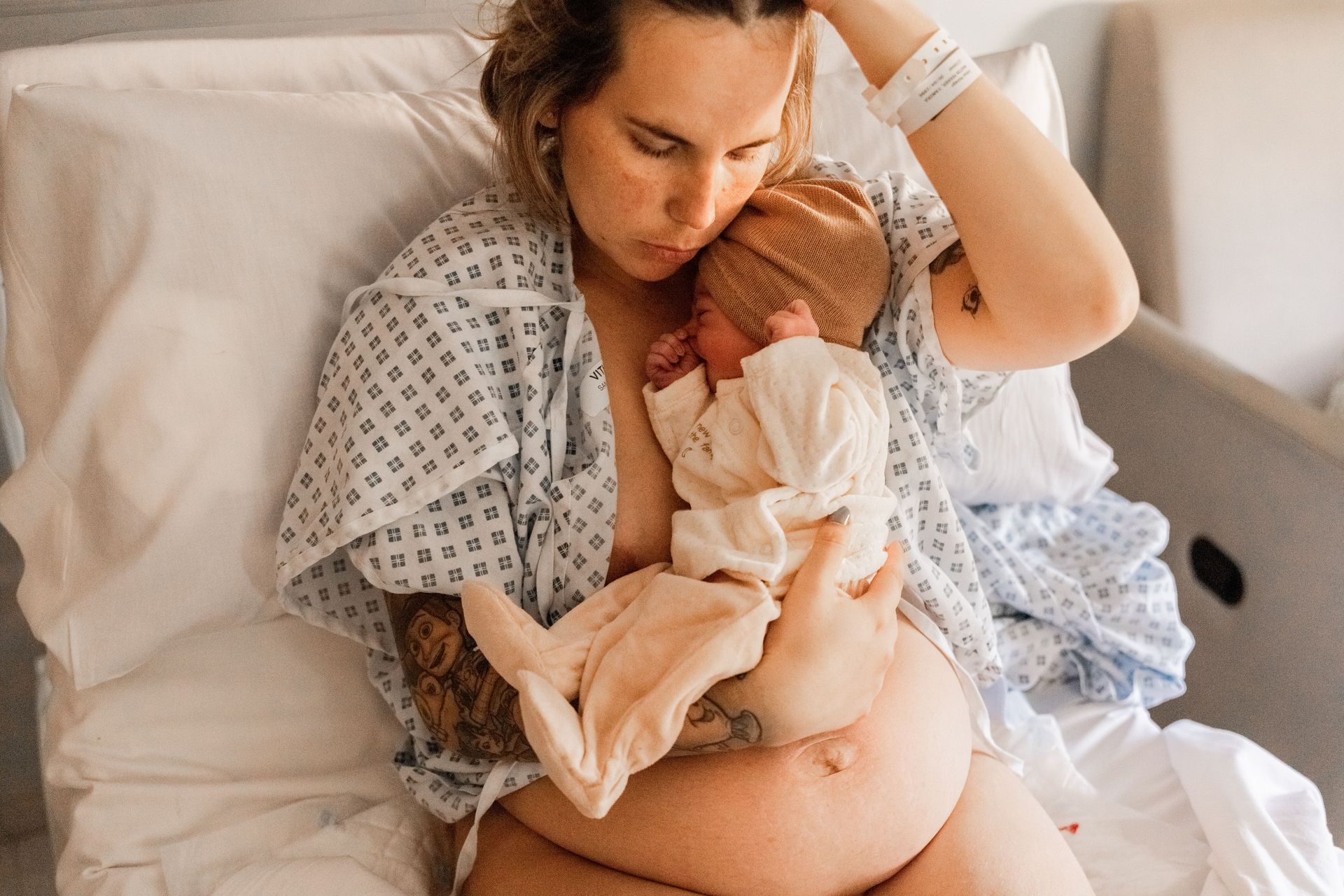 Una mujer sostiene a un bebé recién nacido en una cama de hospital.