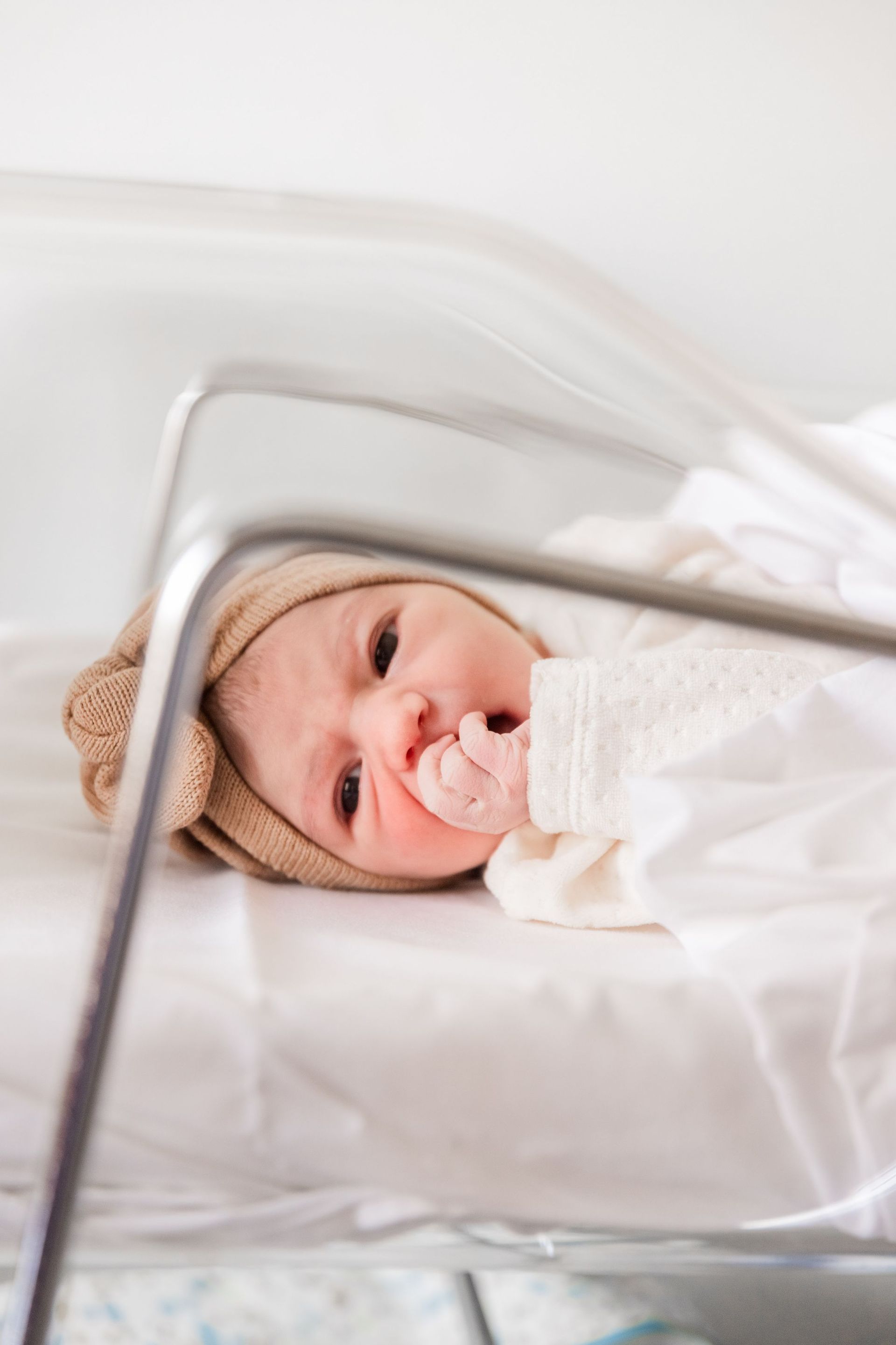 Un bebé recién nacido está acostado en una cuna con un chupete en la boca.