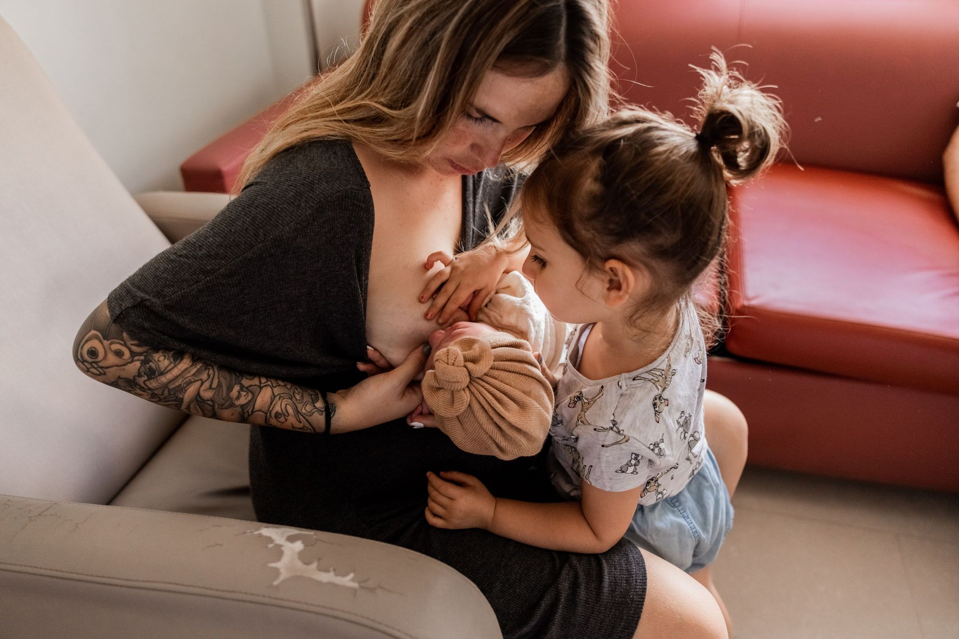 una mujer está amamantando a un bebé mientras una niña mira .