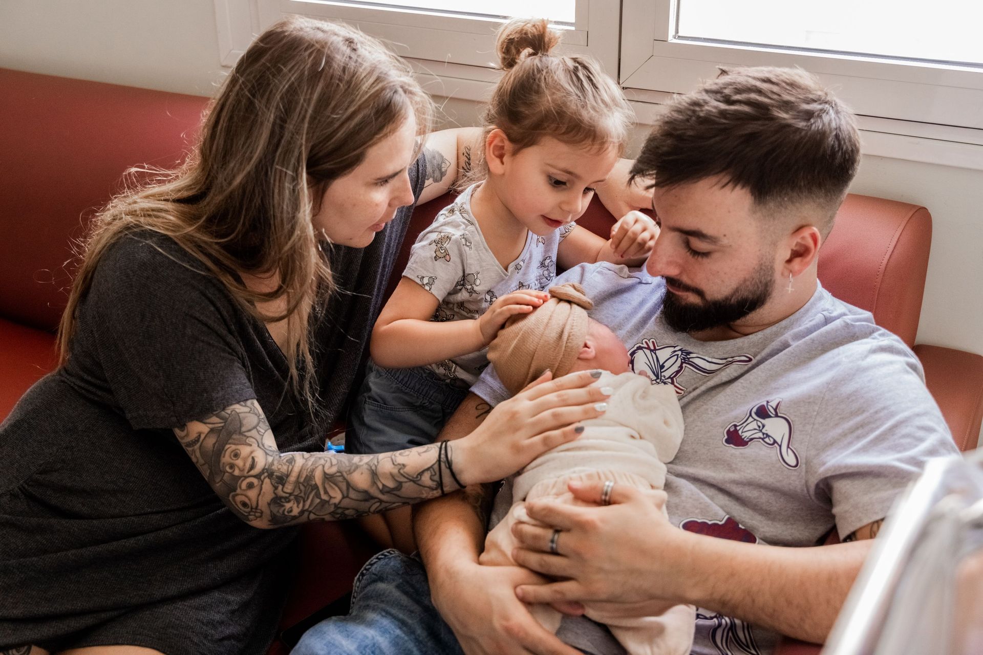 Una familia está sentada en un sofá con un bebé recién nacido.