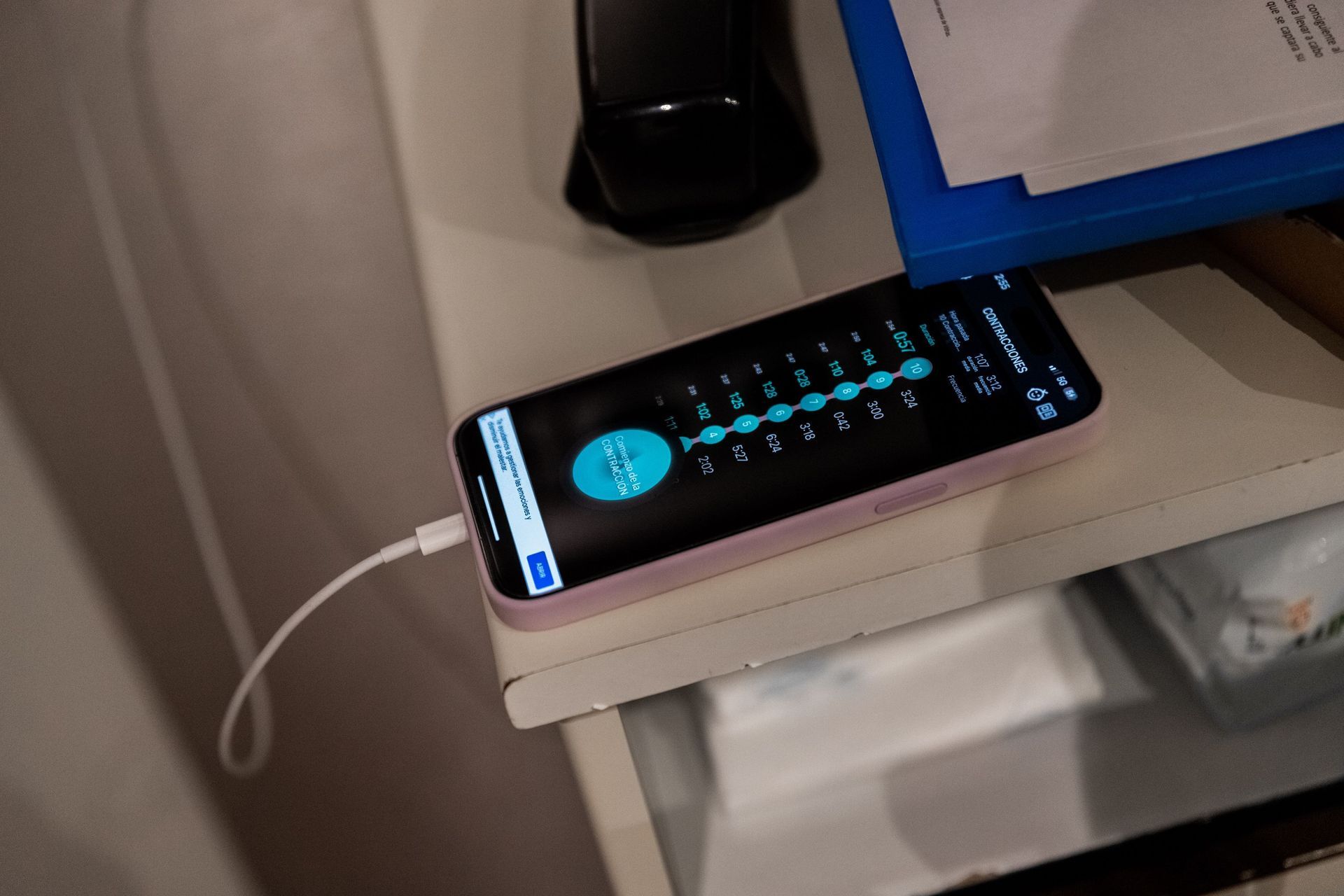 Un teléfono celular está enchufado a un cargador sobre una mesa.