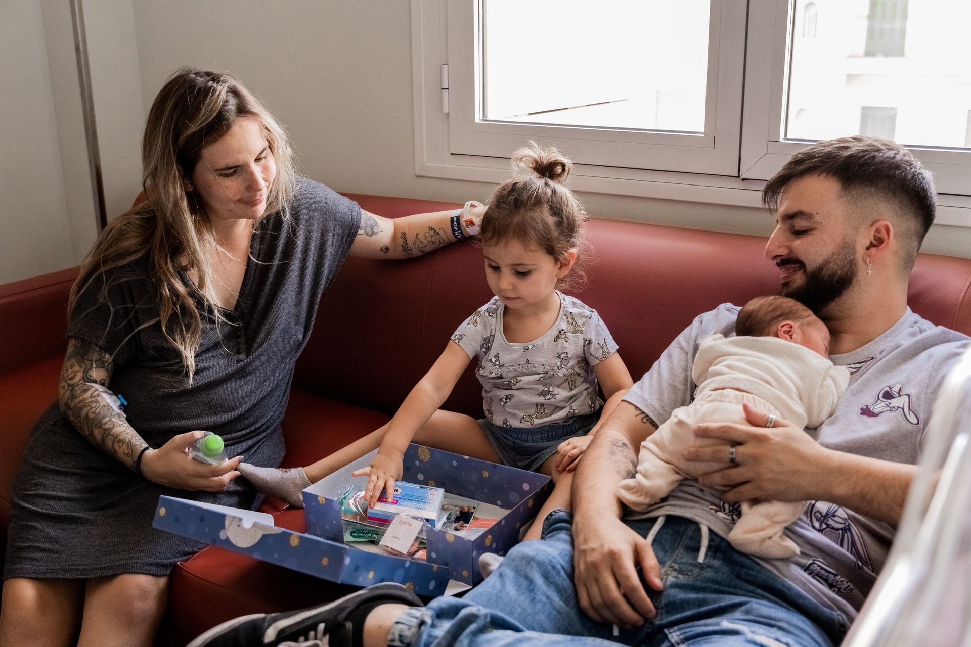 Una familia está sentada en un sofá con un bebé recién nacido.