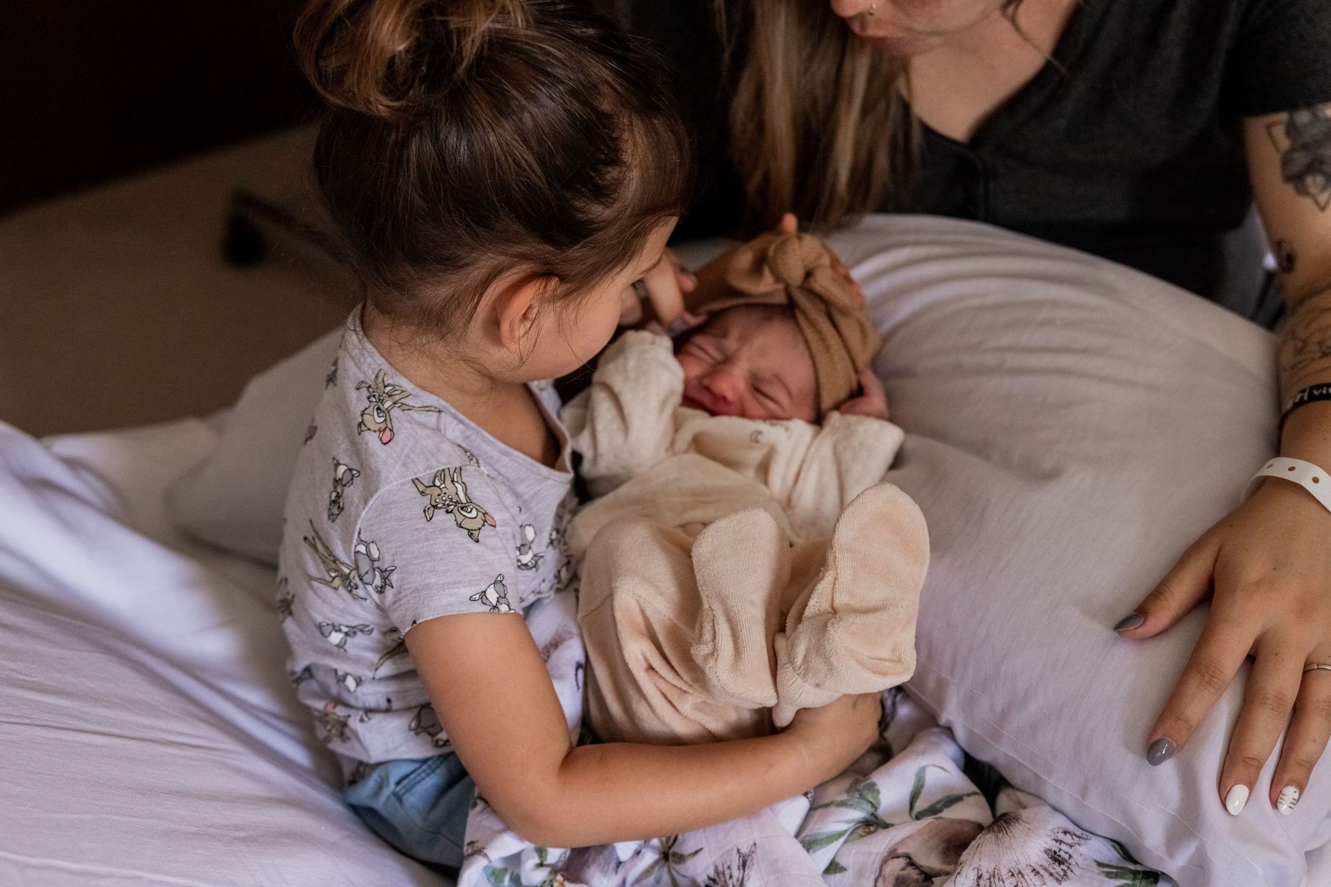 Una niña sostiene en sus brazos a un bebé recién nacido.