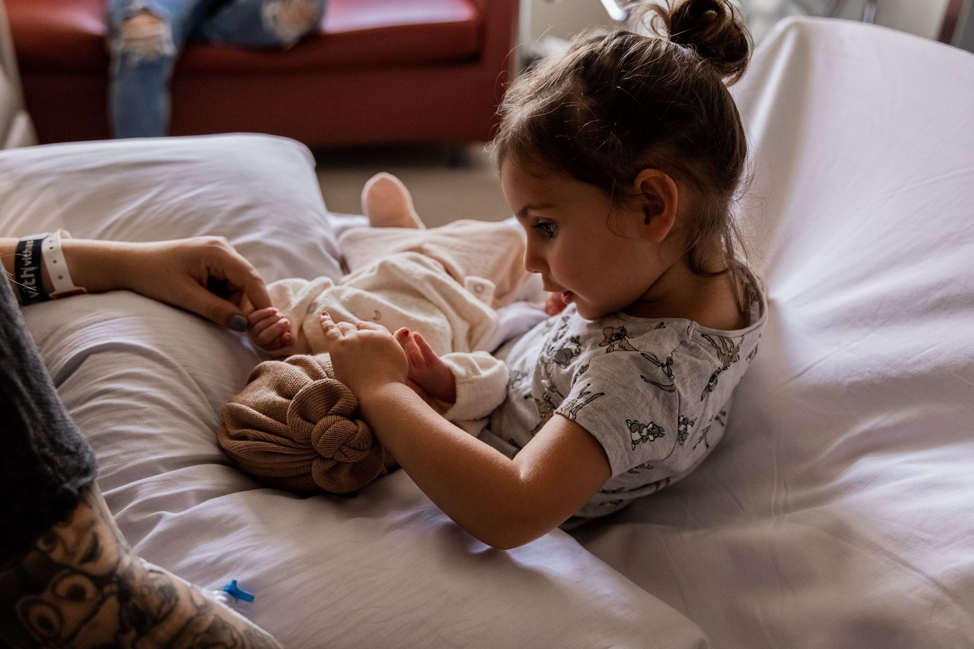 Una niña está acostada en una cama sosteniendo a un bebé recién nacido.