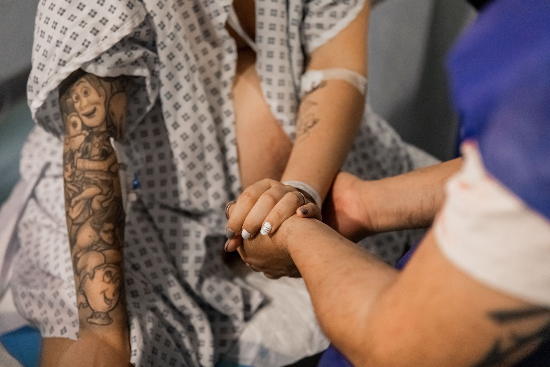 Un hombre y una mujer se toman de la mano en una habitación de hospital.