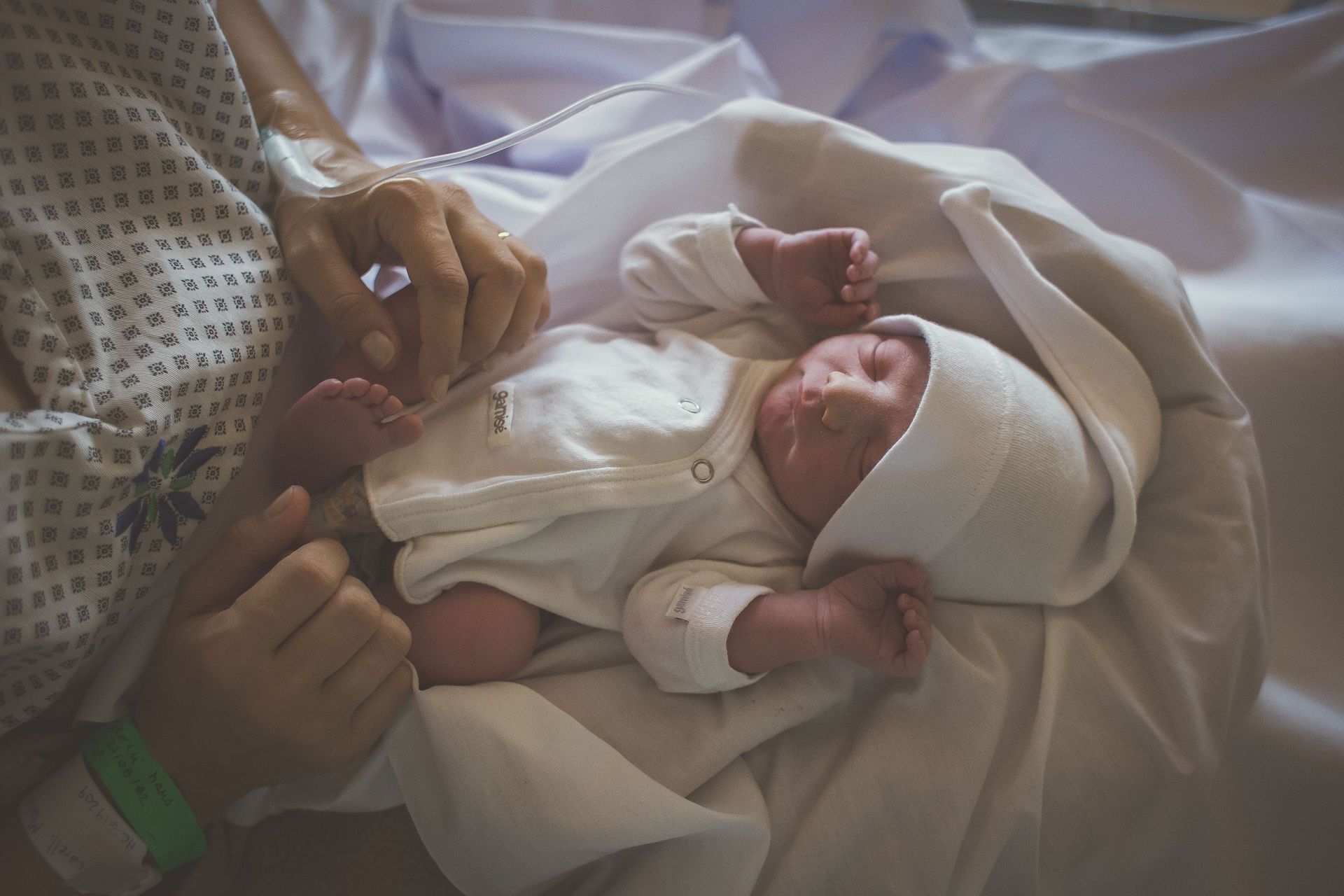 Una persona sostiene a un bebé recién nacido en sus brazos en una cama de hospital.
